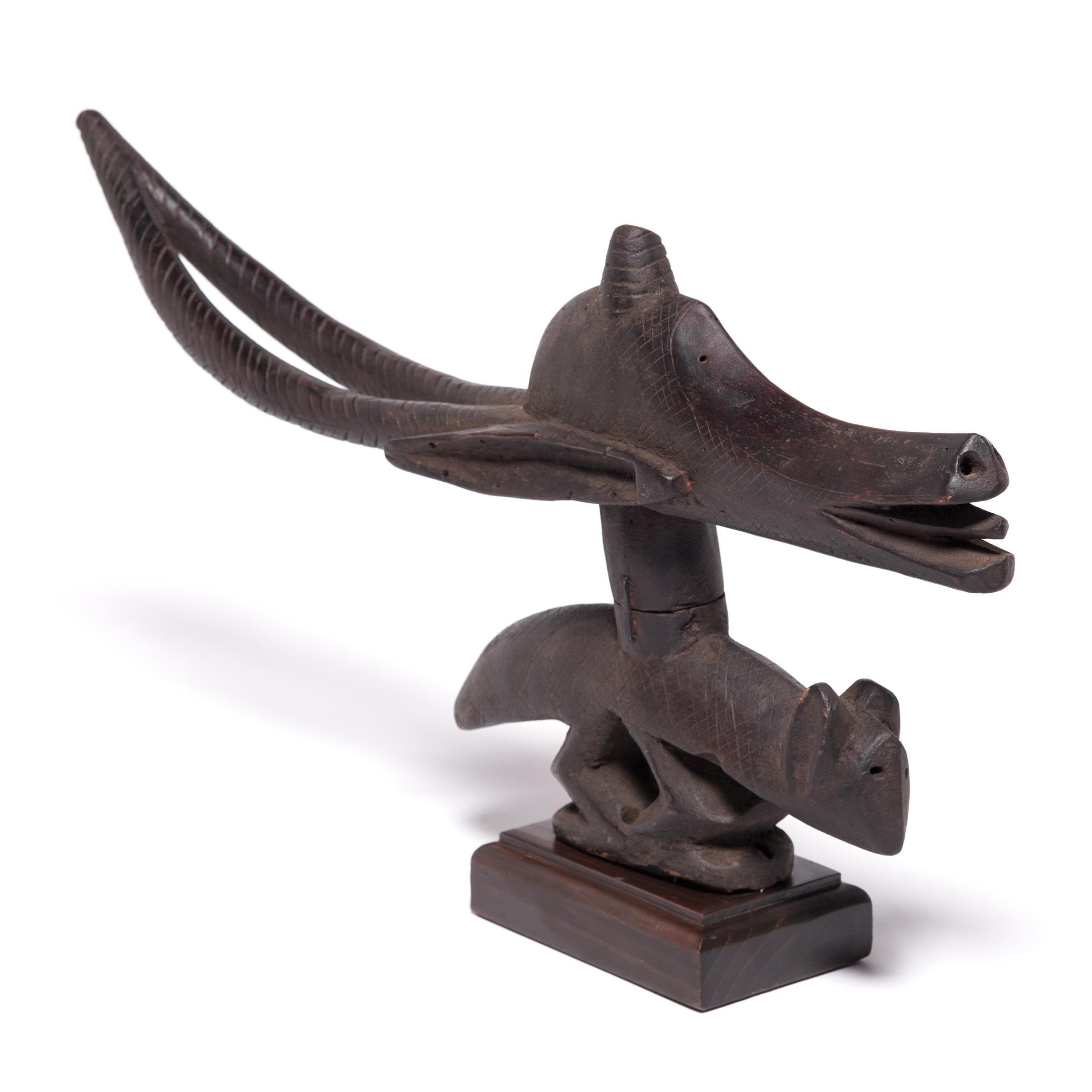 Dieser hölzerne Kopfschmuck wurde zu Ehren des mythischen Wesens Ci Wara geschnitzt, einer Bambara-Gottheit, die halb Mensch und halb Tier ist. Er kombiniert den anmutigen Kopf und die Hörner einer Antilope mit dem kompakten Körper eines
