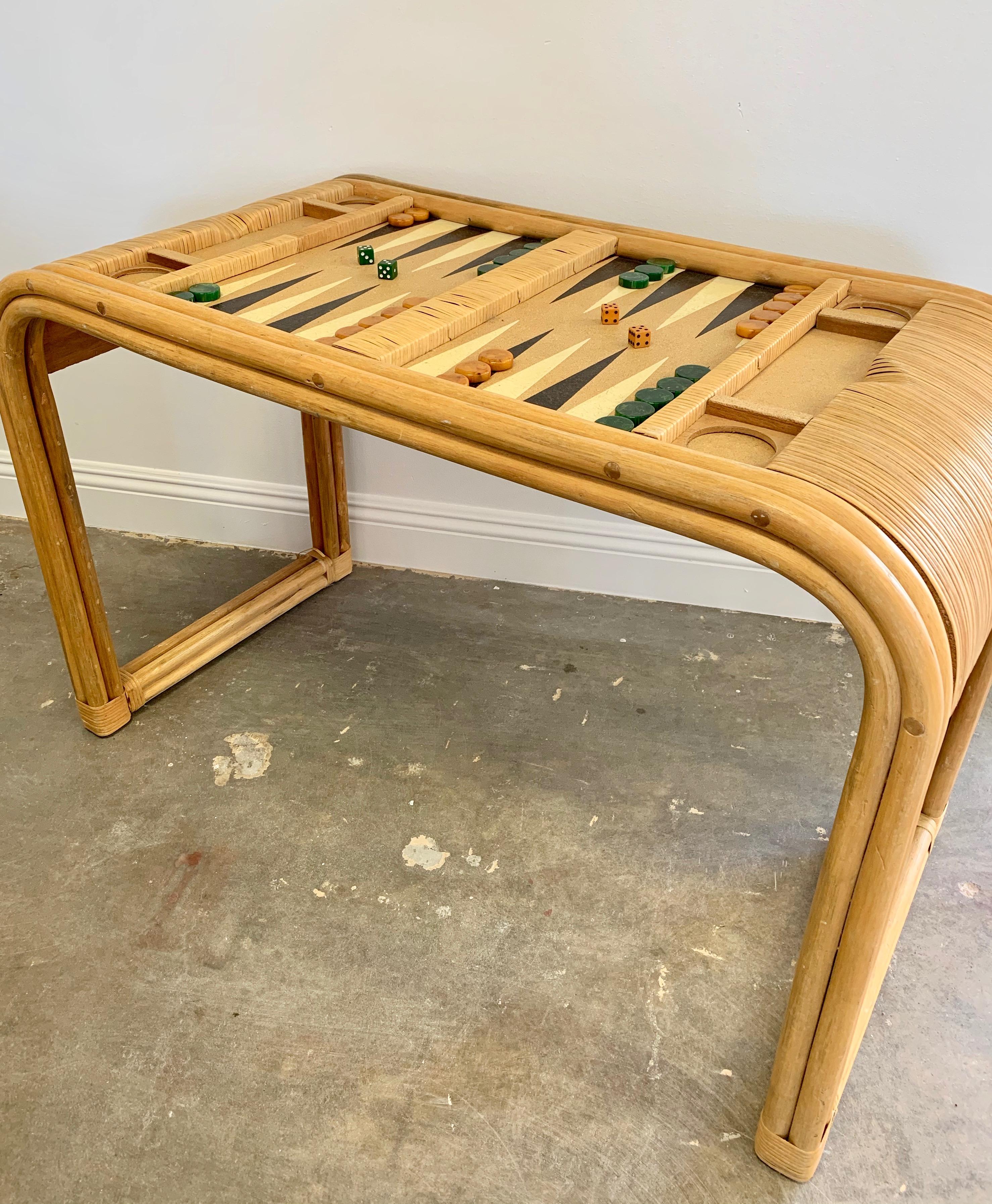 Vintage bamboo, cork and rattan backgammon table with removable glass top. Waterfall edges on both sides with inset drink holders/cubby for game pieces. Game board is made of cork. Table has bamboo frame with rattan wrapping. Good condition. Vintage