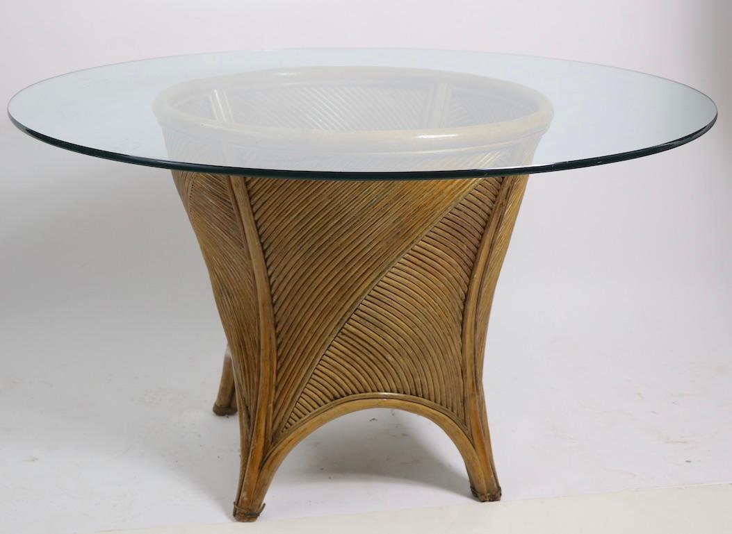 Chic and stylish glass top, bamboo base dining table, in the style of McGuire Furniture. The center pedestal base (20 W x 20 D x 28 Dia. inch) supports a thick (.50 in.) circular glass disk top (48 Dia. in.). Tghis example is in very good original