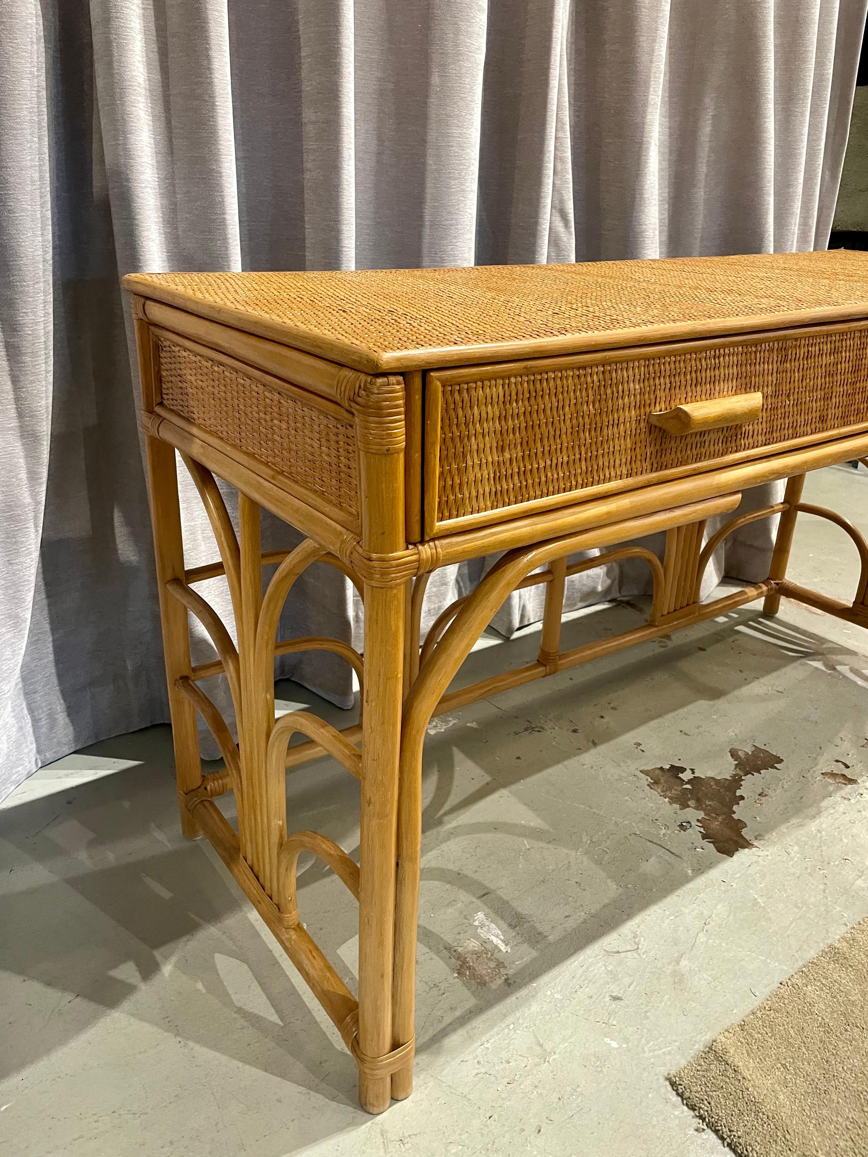 This wonderful console table that can also double as a desk, is comprised of two drawers and a wonderful bent bamboo design throughout. The grass cloth top and sides are in very clean, hardly used condition.