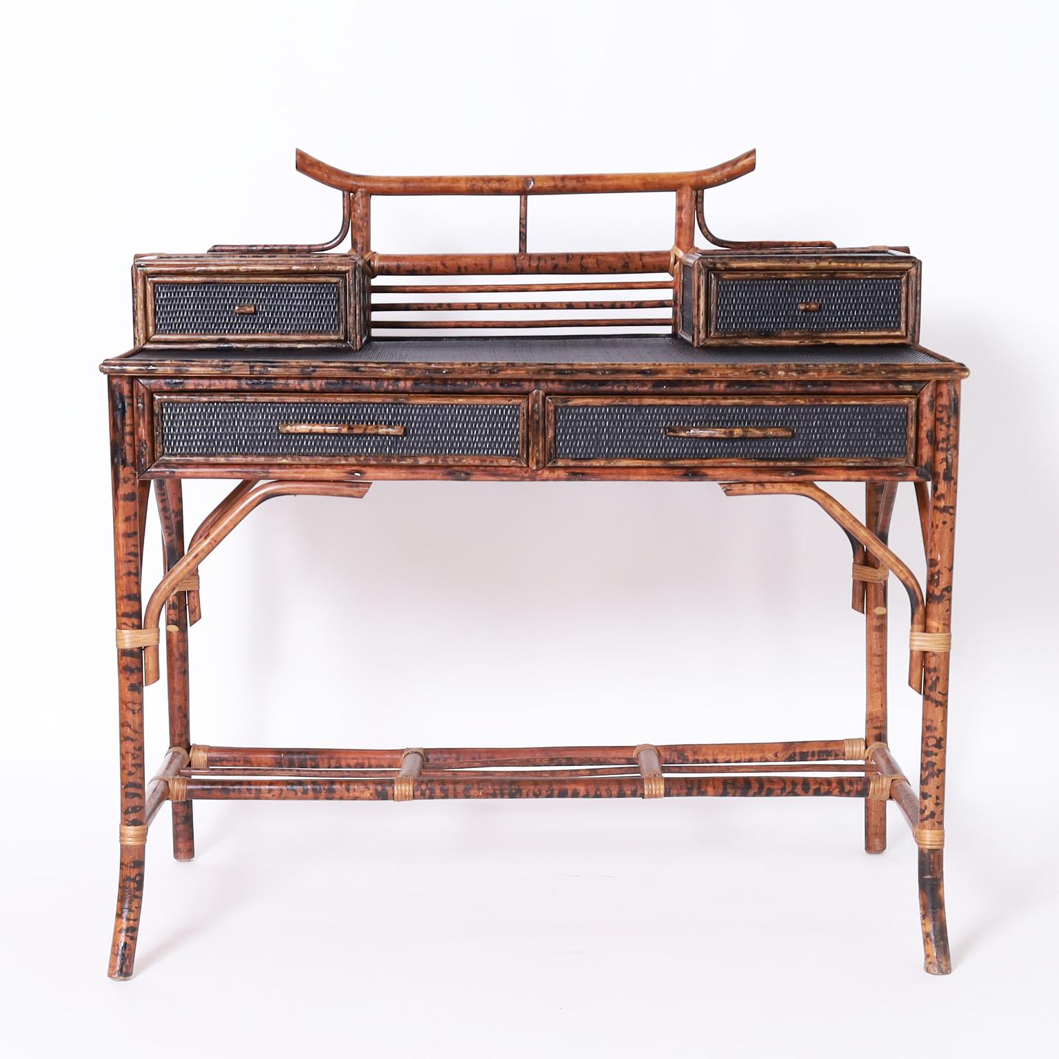 Vintage Asian modern British colonial style desk crafted with a bamboo frame and painted grasscloth panels featuring a pagoda form gallery, two glove boxes, two drawers in front and splayed legs.