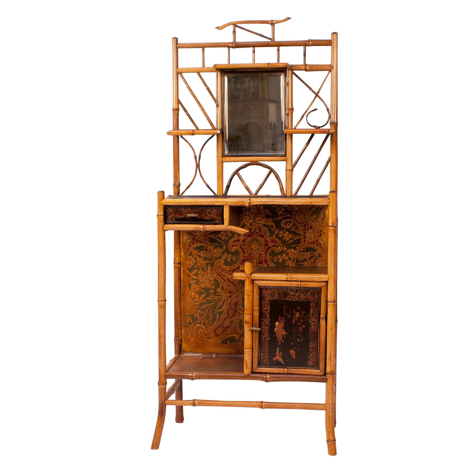 A late 19th century English bamboo shelf with lacquered panels and a dressing mirror, circa 1880. These pieces where popular most of the 19th century and often included lacquered panels inspired by Japanese and Chinese designs. Bamboo furniture was