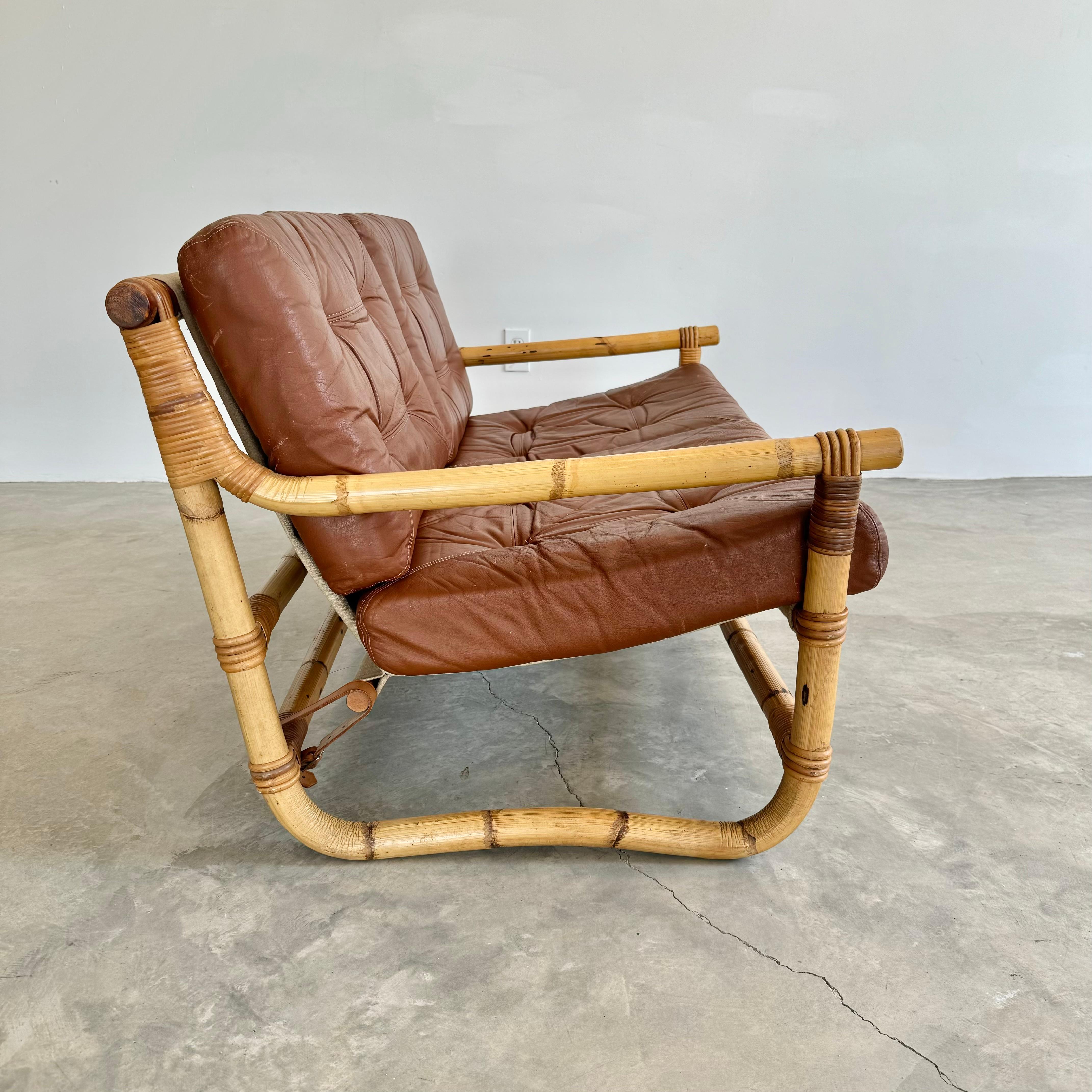 Incredible Danish two-seater leather and bamboo sofa. Great condition and coloring to brown leather with light patina. Frame is made of thick bent bamboo shafts fastened together by strong woven rattan bands. Cushions are removable to allow for