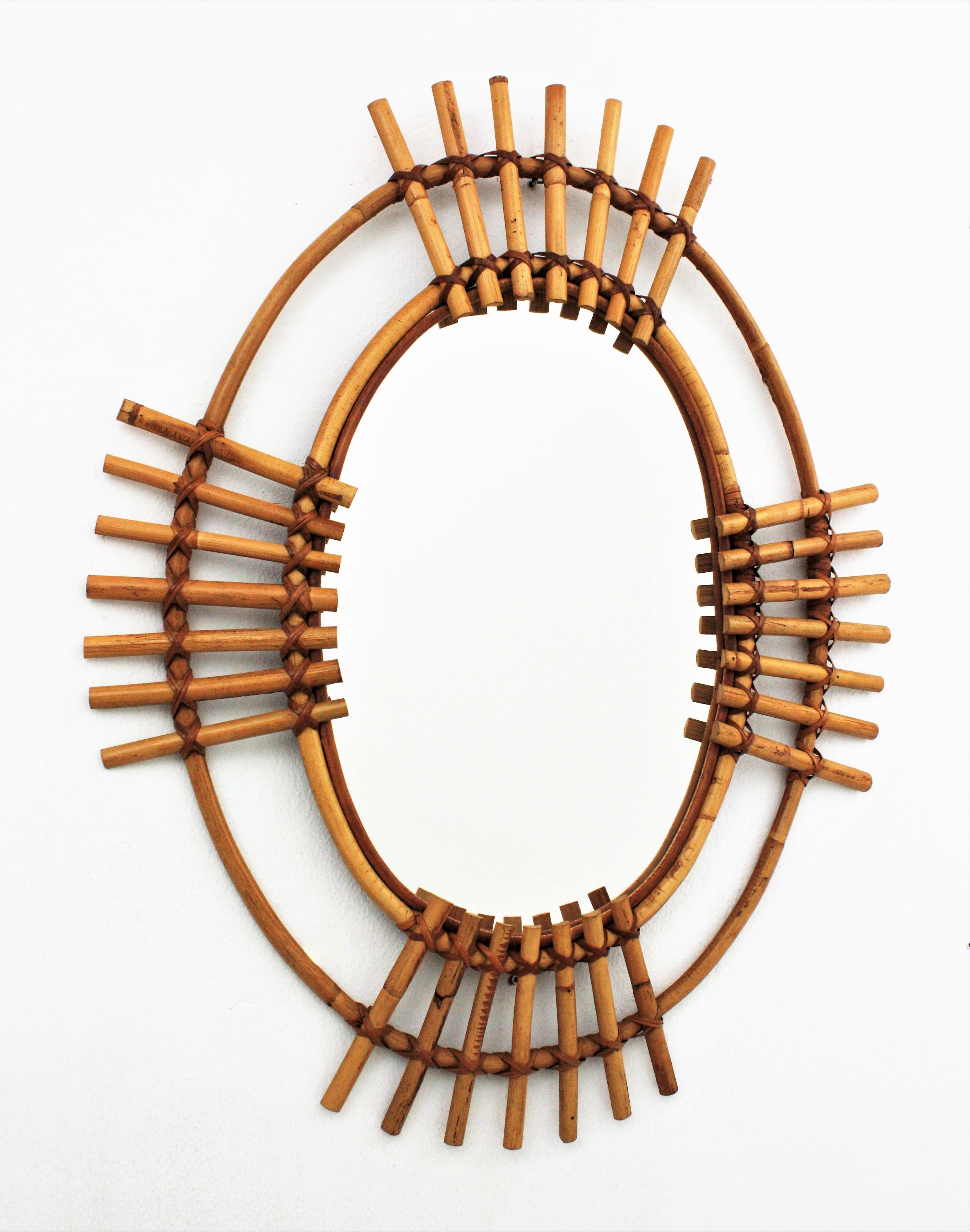 Eye-catching Mid-Century Modern large oval sunburst mirror in bamboo and rattan, Spain, 1960s.
This wall mirror features a double oval bamboo/rattan frame with split bamboo canes in sunburst disposition.
The large mirror surface allows to use it