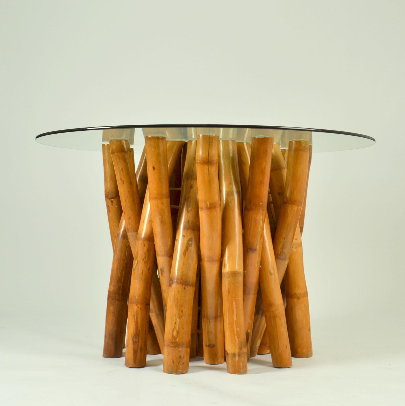 La escultural mesa de comedor de bambú de los años 50 está formada en dos partes, primero un grupo de grandes patas de bambú en forma de círculo y luego un anillo exterior de patas de bambú con una tapa redonda de cristal que descansa encima. El