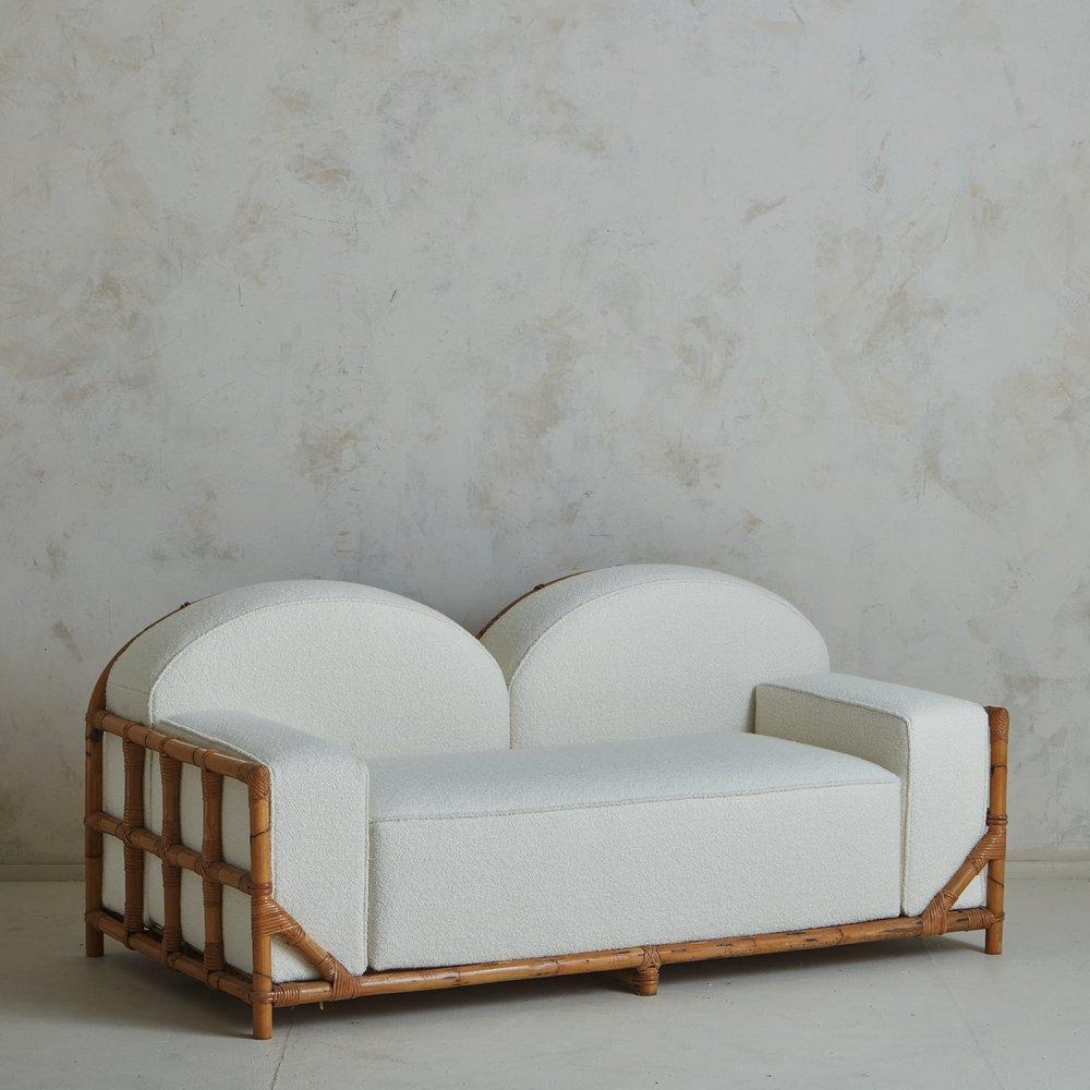 A 1970s Italian sofa featuring a bamboo frame with a double arch back and cane detailing. This sofa has an impressive presence and was newly reupholstered in a beautiful white boucle. Unmarked. Sourced in Italy, 1970s. A matching pair of lounge