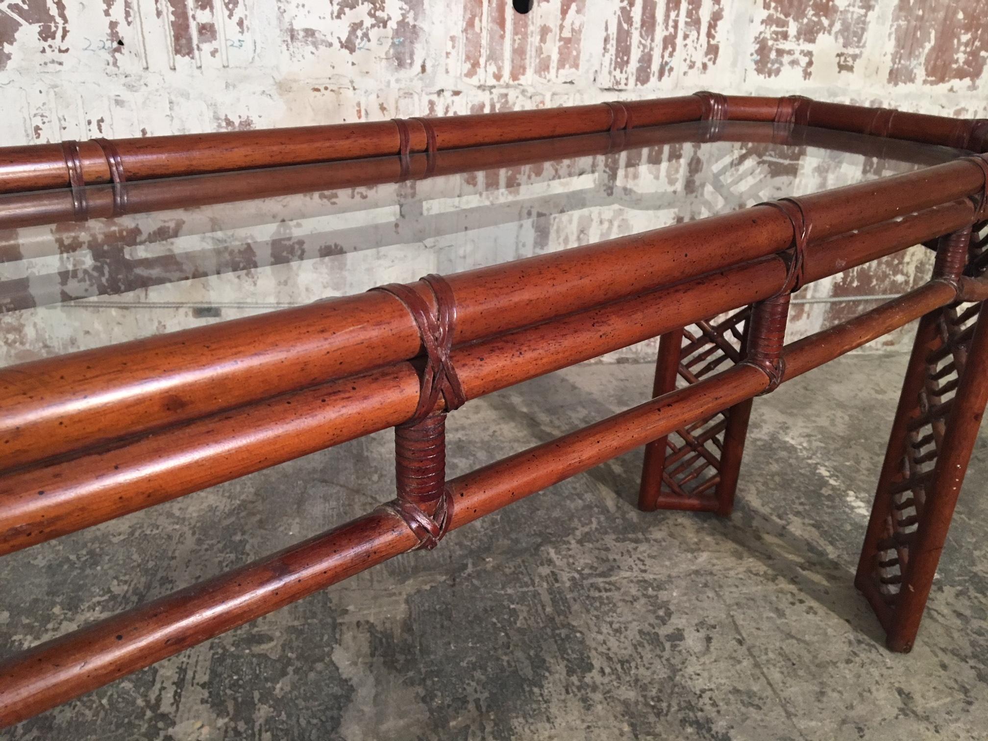 Bamboo console table features Chinese Chippendale detailing and recessed glass top. Perfect touch of chinoiserie styling for any decor. Excellent vintage condition with minor signs of age appropriate wear.