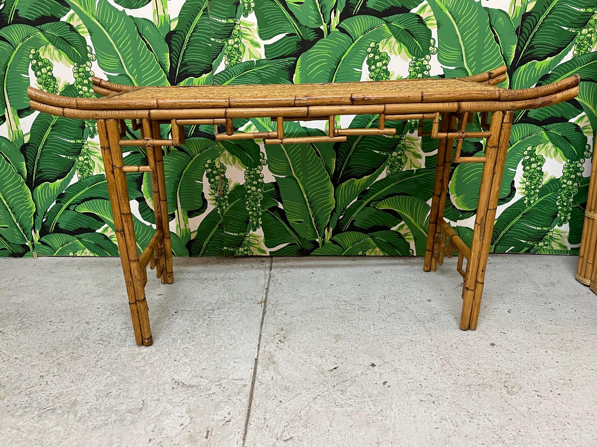 Vintage bamboo console or altar table features Asian chinoiserie styling with everted ends and decorative bamboo apron and spandrels. Top is veneered in woven wicker. Very good condition with only very minor imperfections consistent with age.