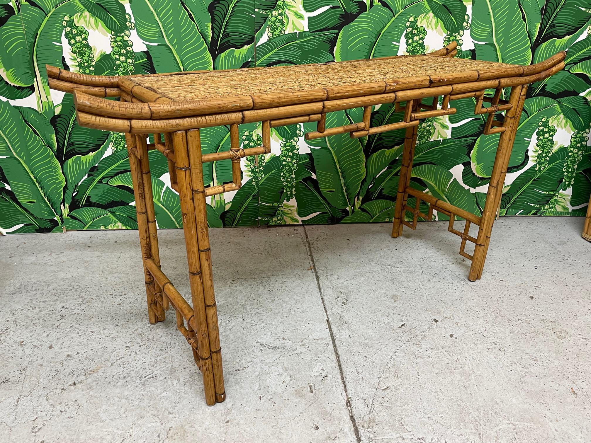 Vintage bamboo console or altar table features Asian chinoiserie styling with everted ends and decorative bamboo apron and spandrels. Top is veneered in woven wicker. Very good condition with only very minor imperfections consistent with age.

 