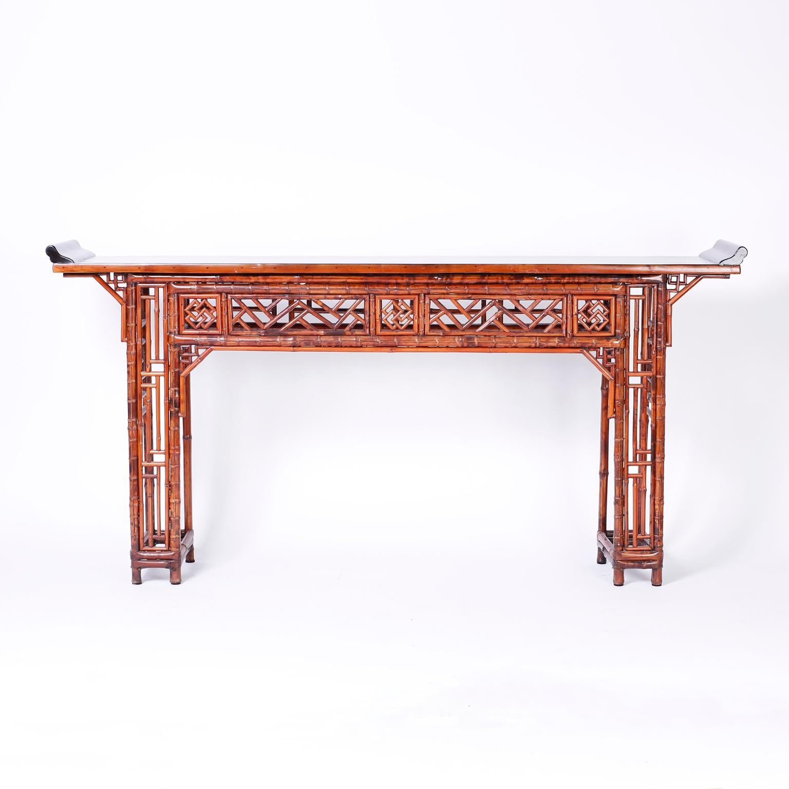 Chinese chinoiserie console or altar table with an ebonized top. The bamboo base features a desirable slim profile and decorative panel in the Chippendale style on the skirts and adjoining eight legs.