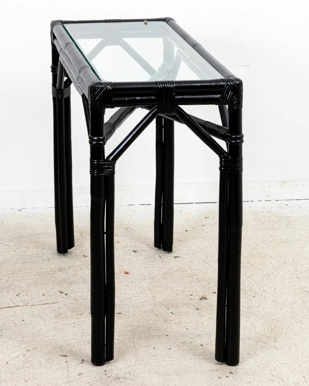 circa late 20th century Hollywood Regency style bamboo console table in a black painted finish with newer glass top. Please note of wear consistent with age. Good overall condition.