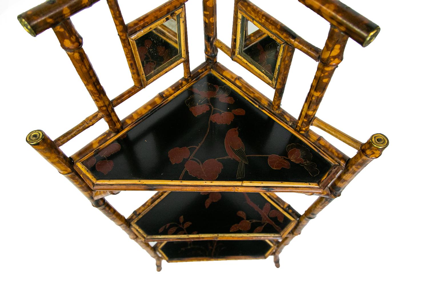 Bamboo corner shelf has two square mirrors in the upper back panels. The bamboo ends are capped with brass rosettes. All three shelves have Asian lacquer painting framed by split bamboo.
 