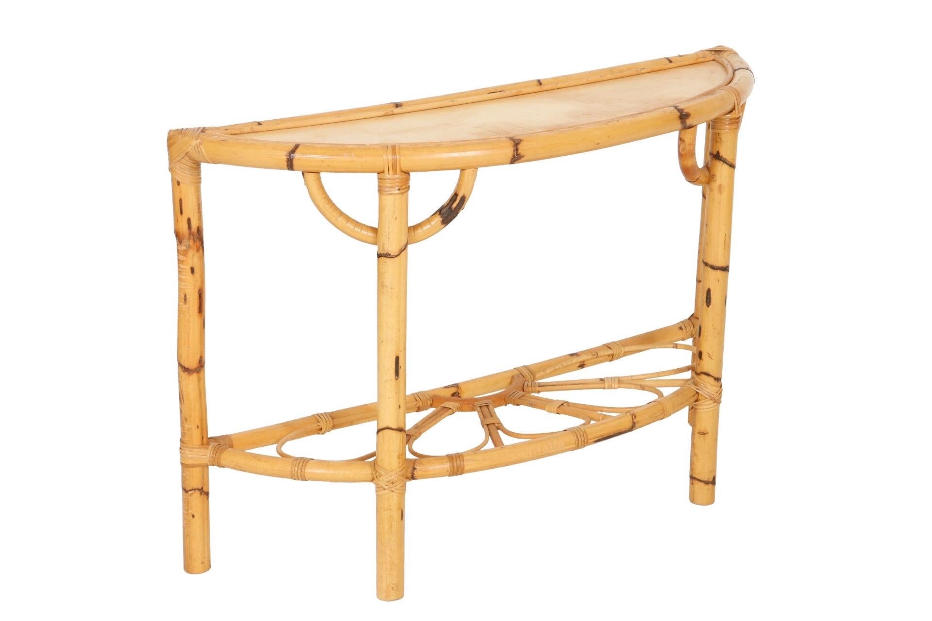 A bamboo demilune hall table. Thick bamboo pieces form the frame with bentwood bamboo C curve supports at the top of the front legs. Below, bentwood pencil bamboo forms a decorative daisy stretcher. Joins are secured with fine rattan wrapping.