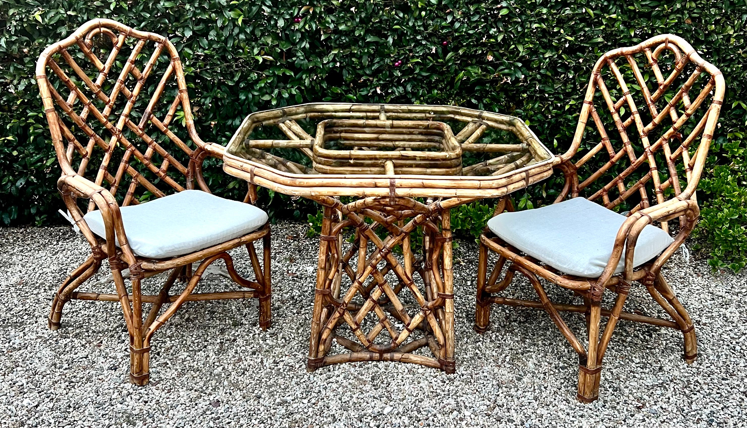 A wonderfully detailed Bamboo Dining Table with Two matching chairs in the style of Louis Sognot.  The set is well made, sturdy and in very good condition.   The lashing is leather and also in very good condition.  

The set would be a compliment to