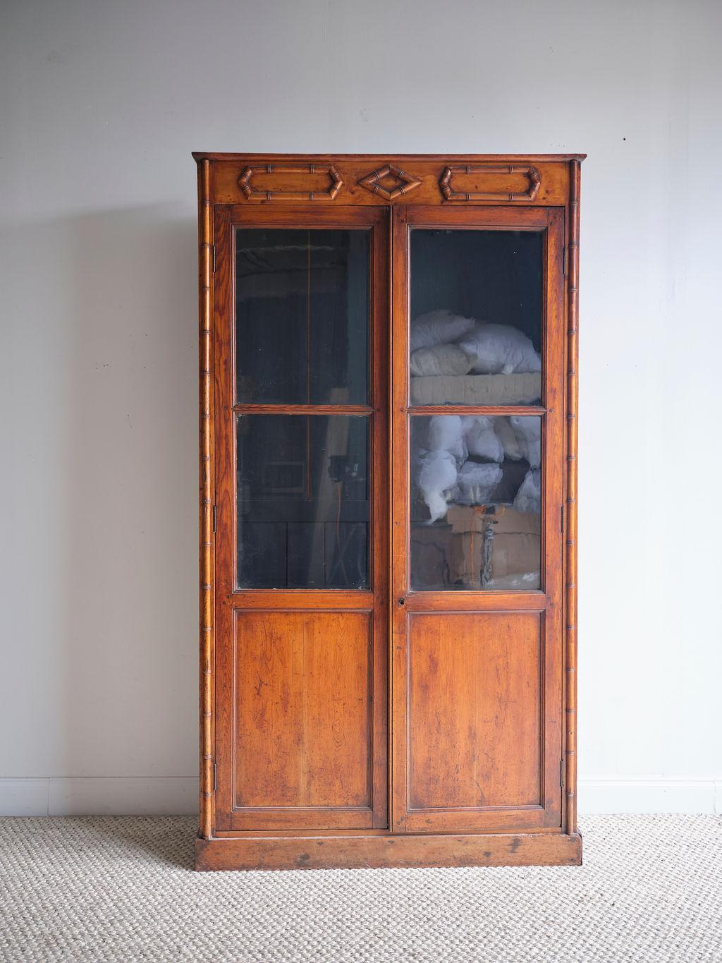 This bamboo glazed cabinet features a lovely warm patina and bamboo features along the sides of the piece as well as across the top. The four window panes are original and in great shape. The cabinet opens up to four interior shelves that are each 9