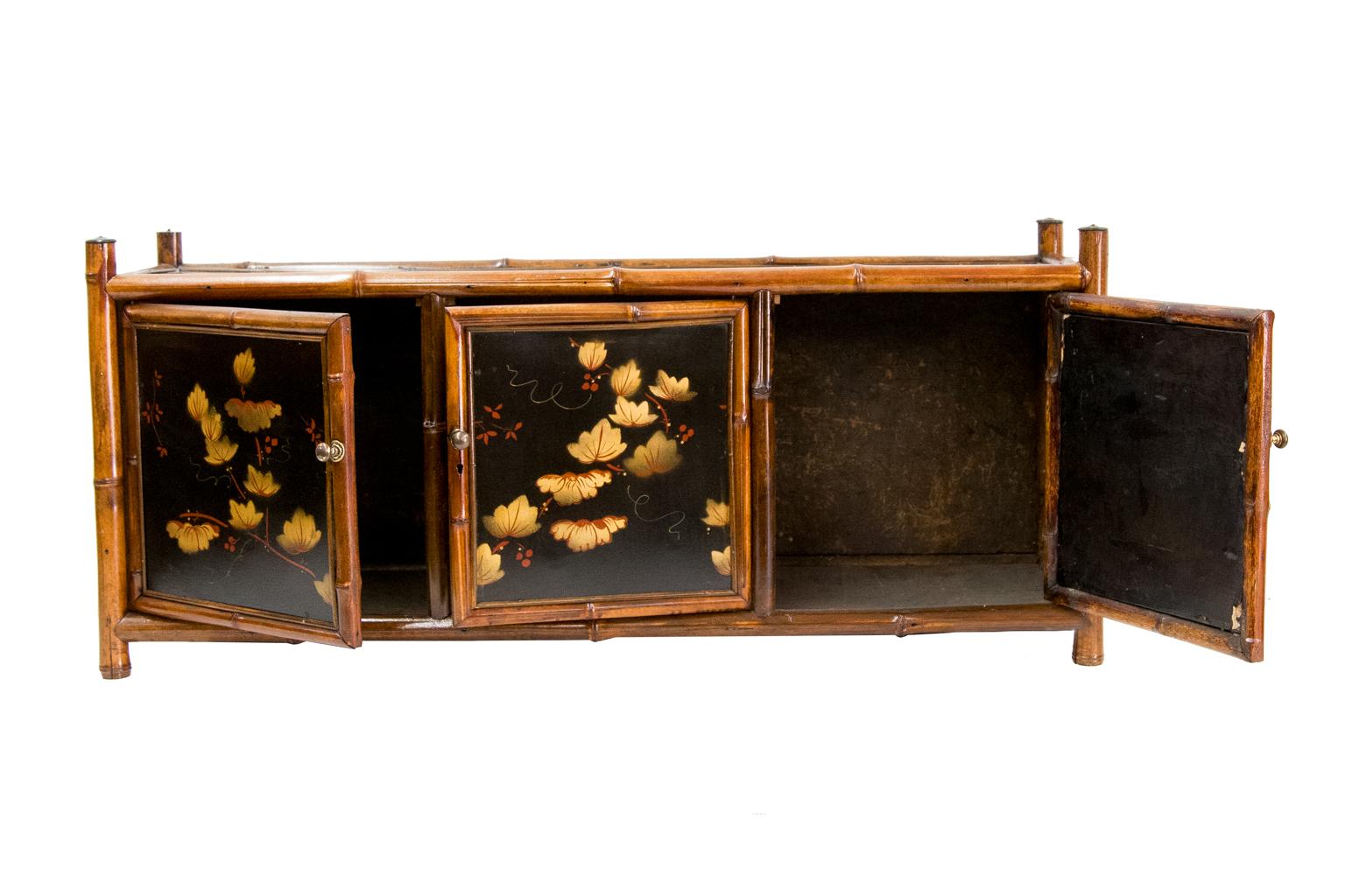 Bamboo lacquer three-door cabinet can be used as a counter top cabinet or hung on the wall. It has a heavy bamboo frame with leaf and berry motif with lacquer panels on the top, sides, and doors.