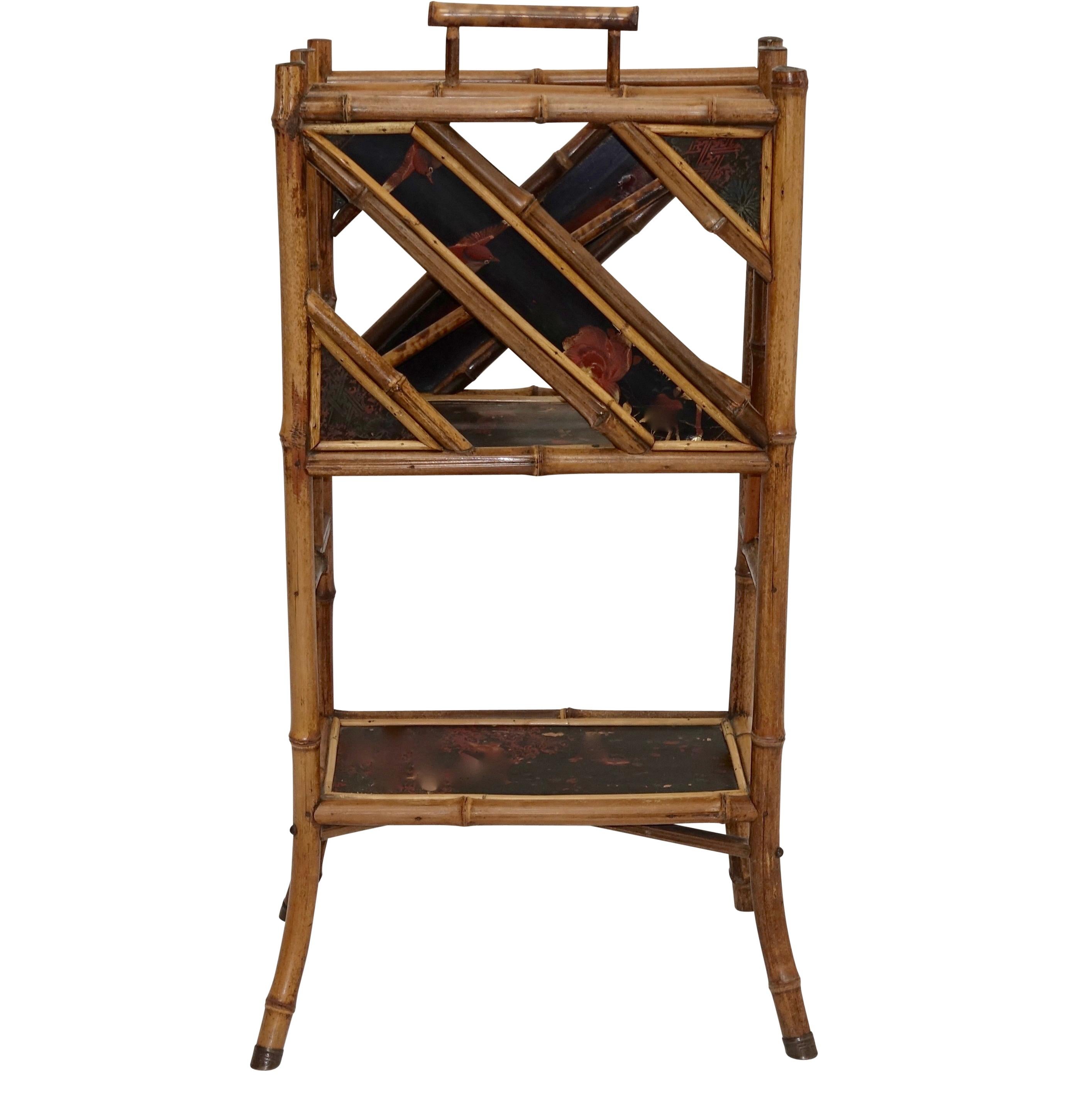 Victorian bamboo magazine stand with inset Japanese lacquer panels, side panels running on a diagonal with two lacquer panels. Embossed brass disks decorate the top of the bamboo ends and brass feet on the ends of the bamboo legs. English, circa