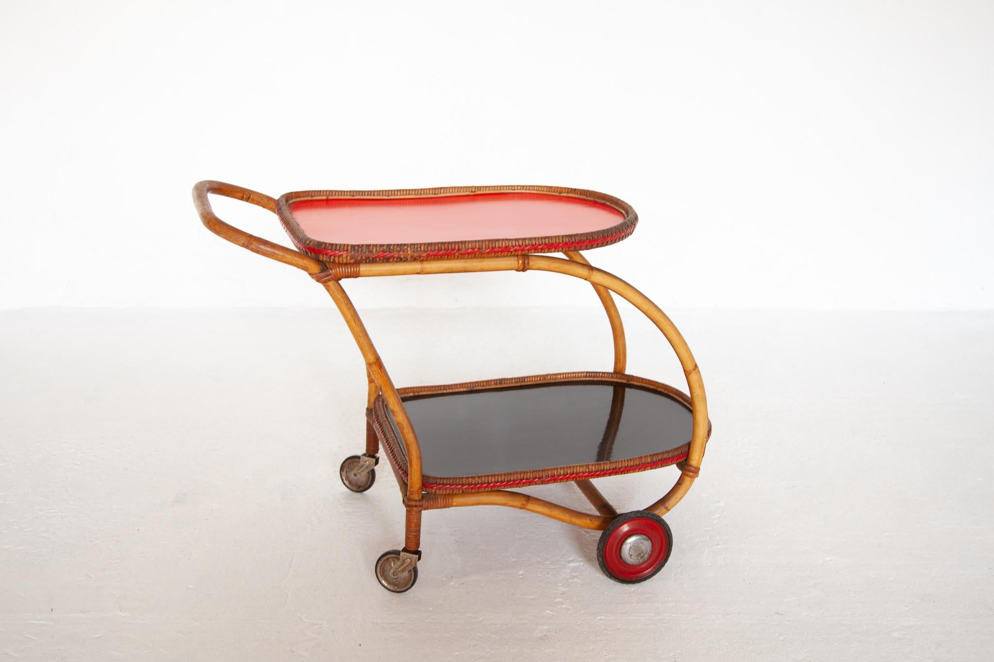 Rare Fifties designed bar cart a quality workmanship made in Italy. The bar cart featured a bamboo frame, the plateaus are laminated in red and black oval shaped in original very good condition with a nice patina and fully functional usable and
