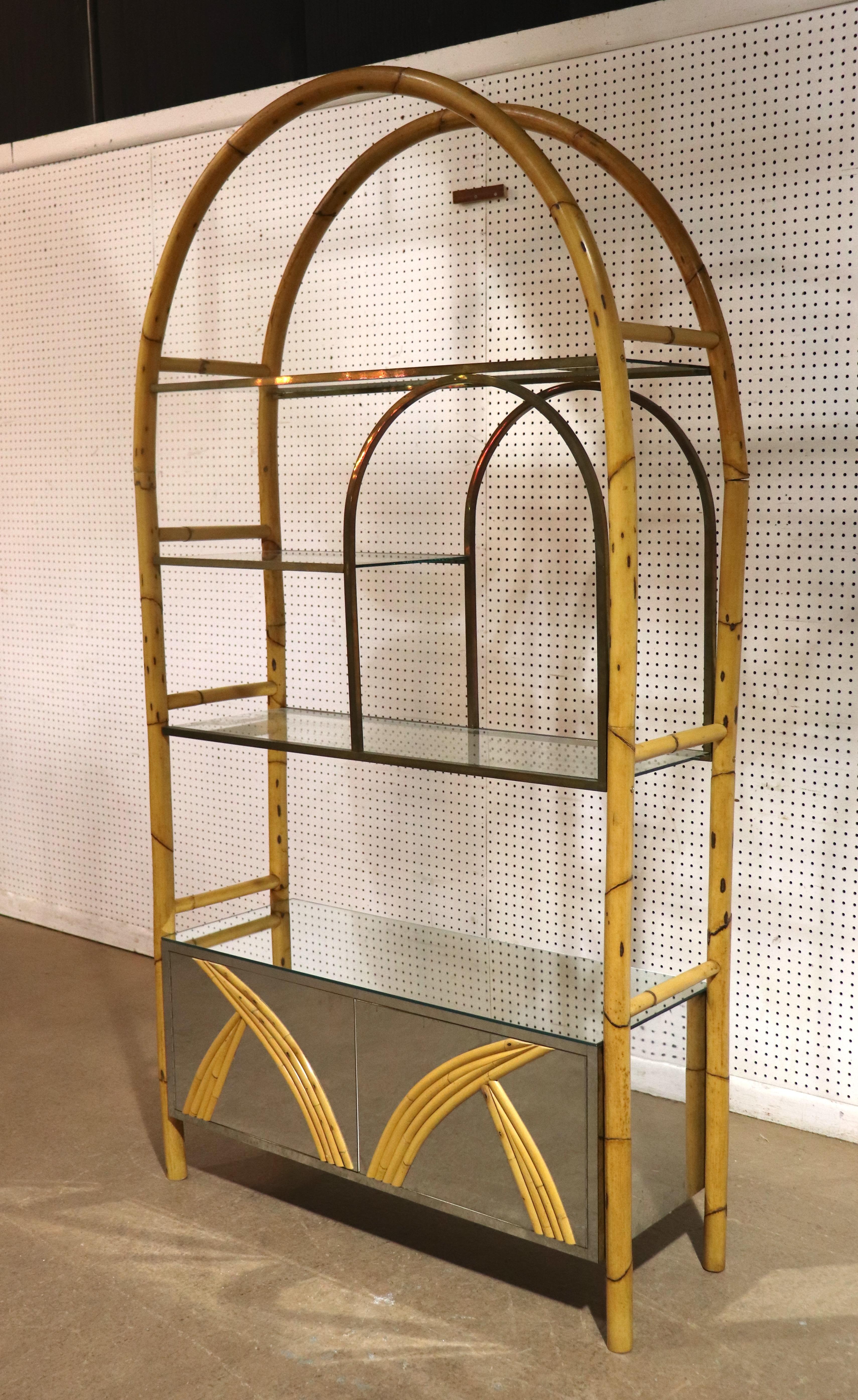Libreria in piedi di metà secolo moderno composta da un mobile a specchio, scaffali in ottone e una struttura in bambù. Un design fantastico con un piano ad arco e porte anteriori in bambù abbinate.
Si prega di confermare la posizione NY o NJ
