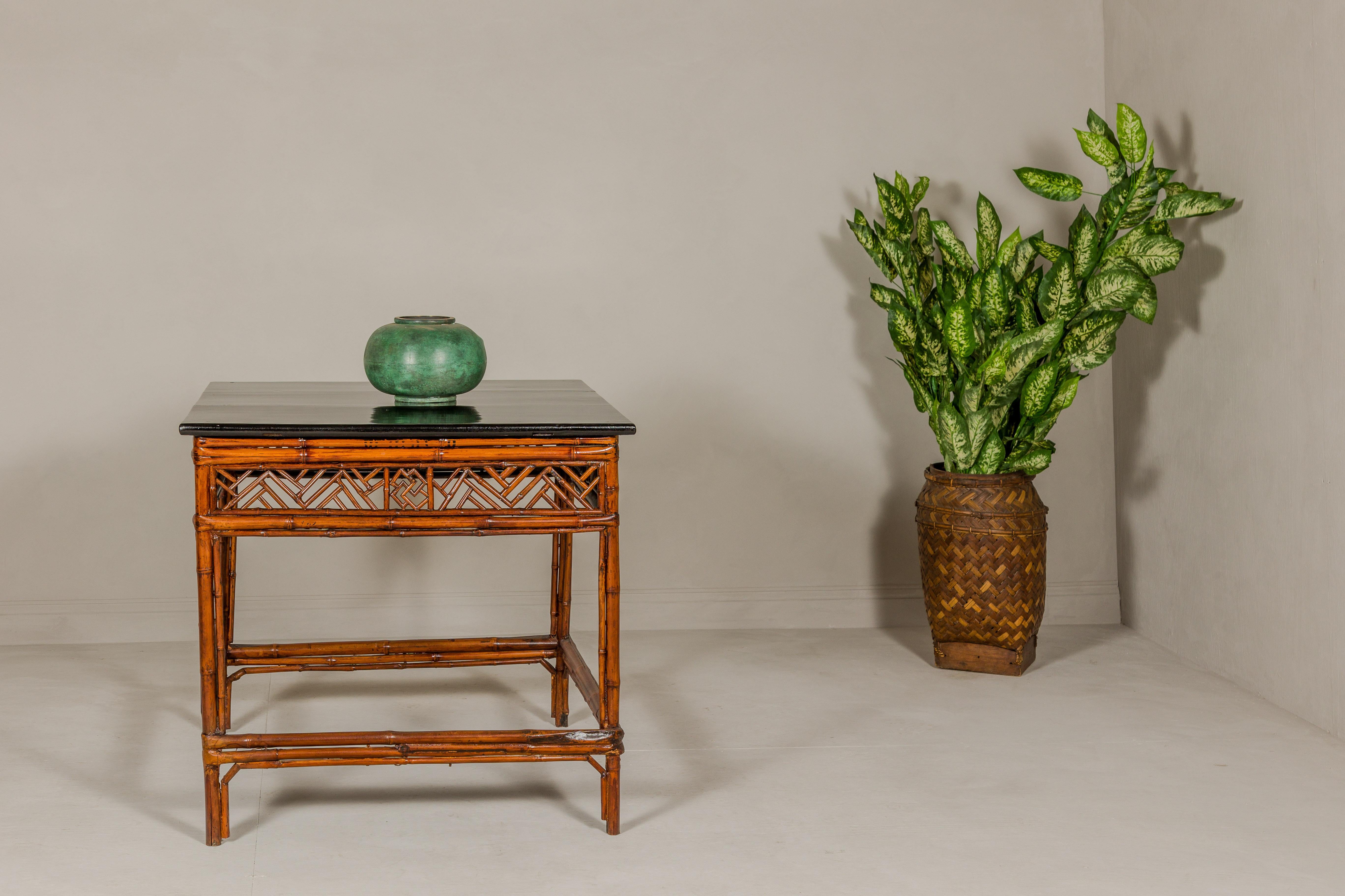 A Chinese Qing Dynasty bamboo square shaped center table with geometric apron and black lacquered top. This Chinese Qing Dynasty bamboo center table, with its square shape and distinctive design, is a remarkable piece that reflects the intricate