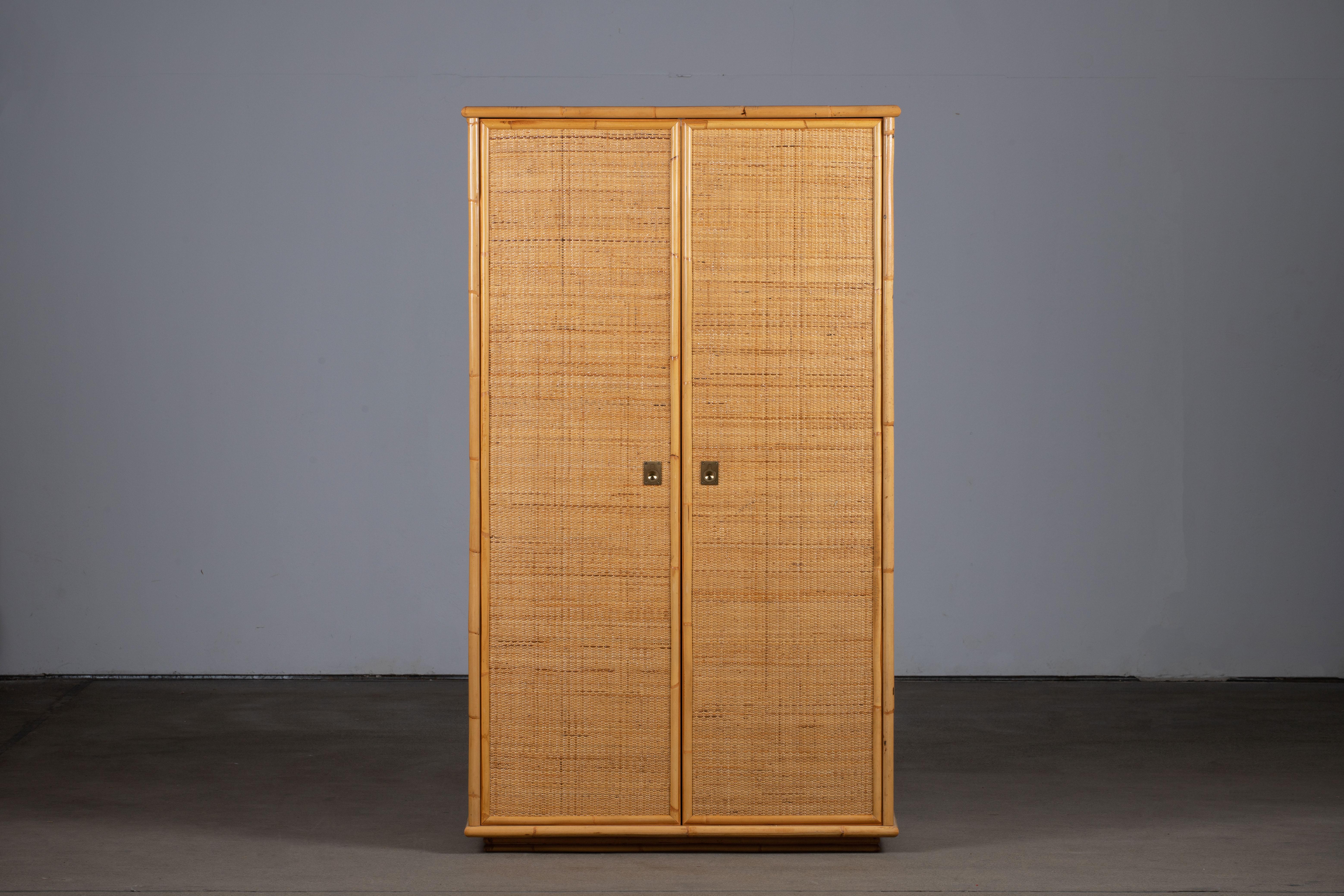Magnifique armoire vintage en rotin et bambou fabriquée par Dal Vera en Italie dans les années 1960. Il est doté d'une double porte qui s'ouvre sur un espace de suspension. Des poignées en laiton complètent l'ensemble. Une superbe pièce vintage en