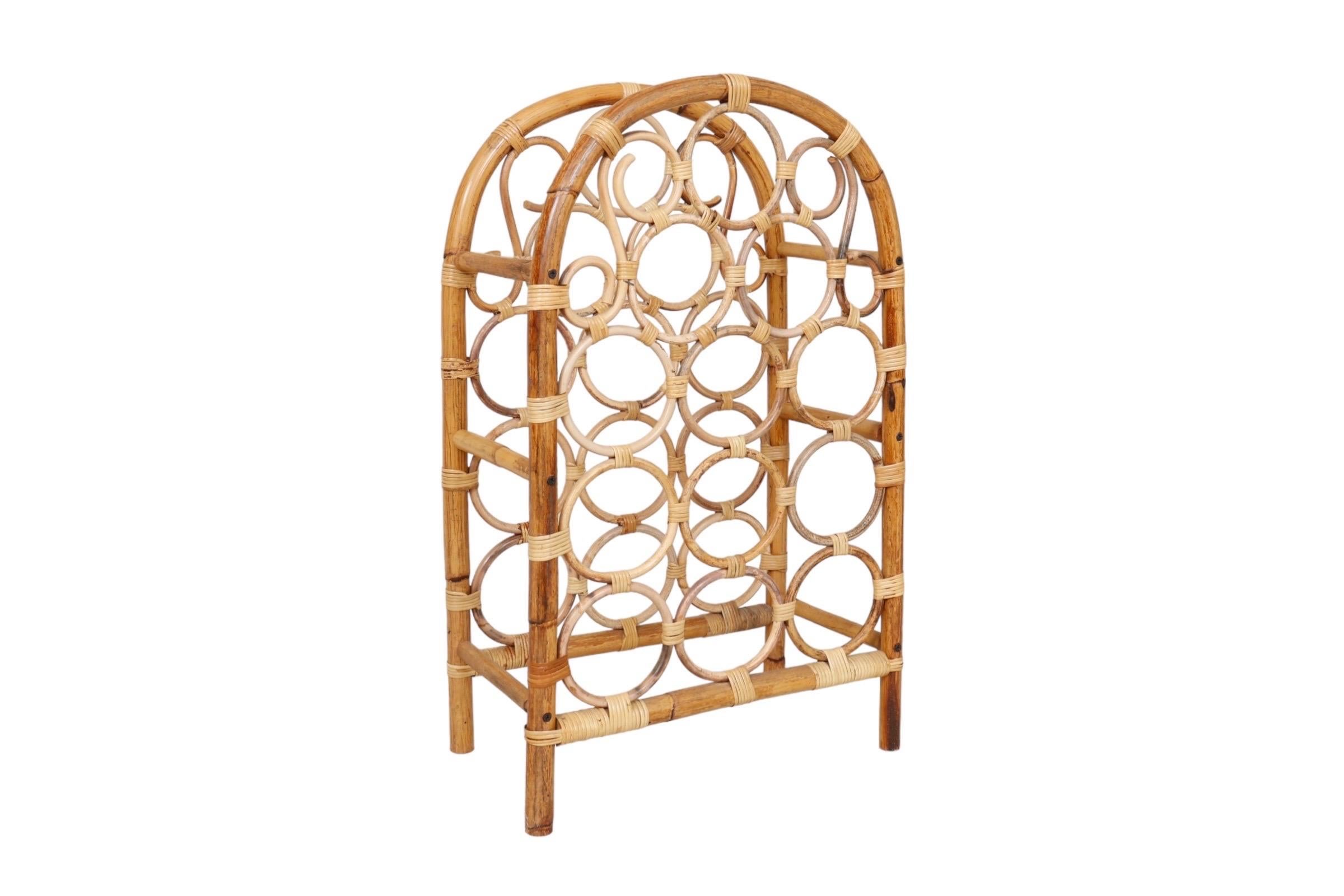 A bamboo and rattan arch shaped wine rack, designed to hold twelve bottles of wine. Pencil wood circles are secured with rattan wrapping stacked three over nine, decorated with pencil wood s-scrolls at the top. 