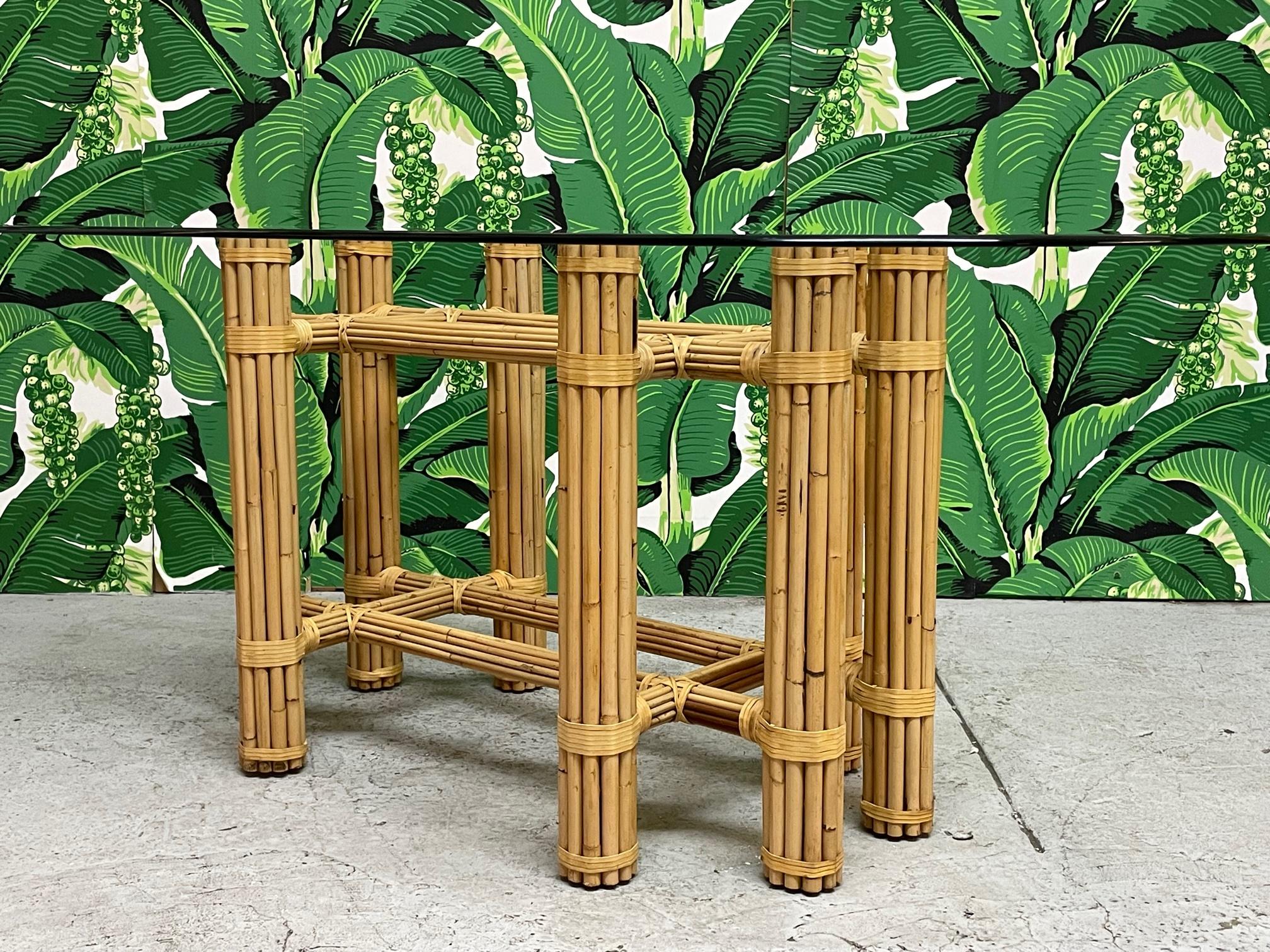 Bamboo rattan glass top dining table in the style of McGuire. Simple and elegant organic modern style. Rattan poles lashed together with leather rawhide laces. Glass top with beveled edge. Base alone measures 40.5