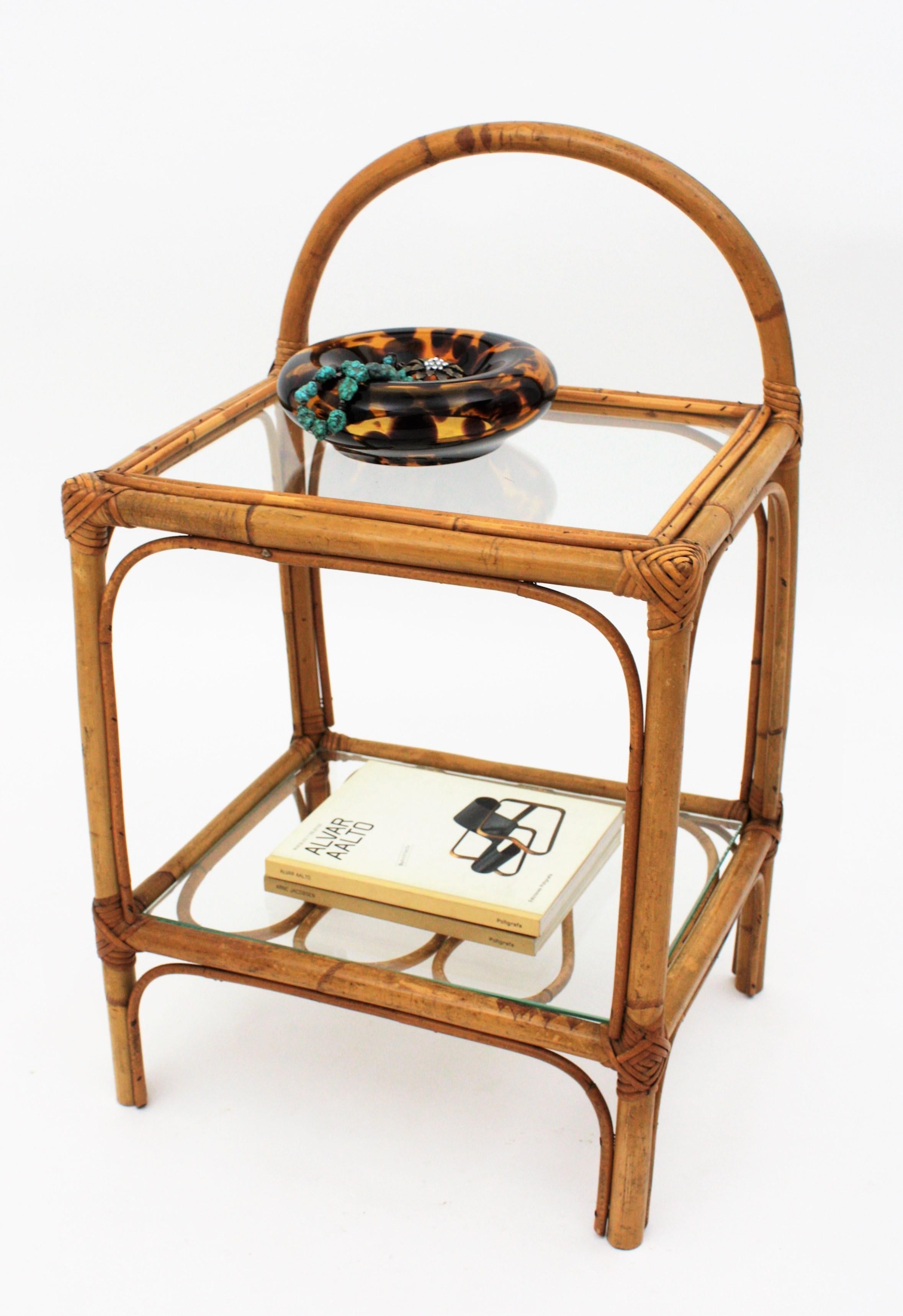 Handcrafted bamboo and rattan Mid-Century Modern table with rattan adorned shelf and glass top, Spain, 1950s.
Use it as bedside table, side table or end table.
Beautiful to be placed indoor in a Mediterranean or Tiki decoration, but also lovely to