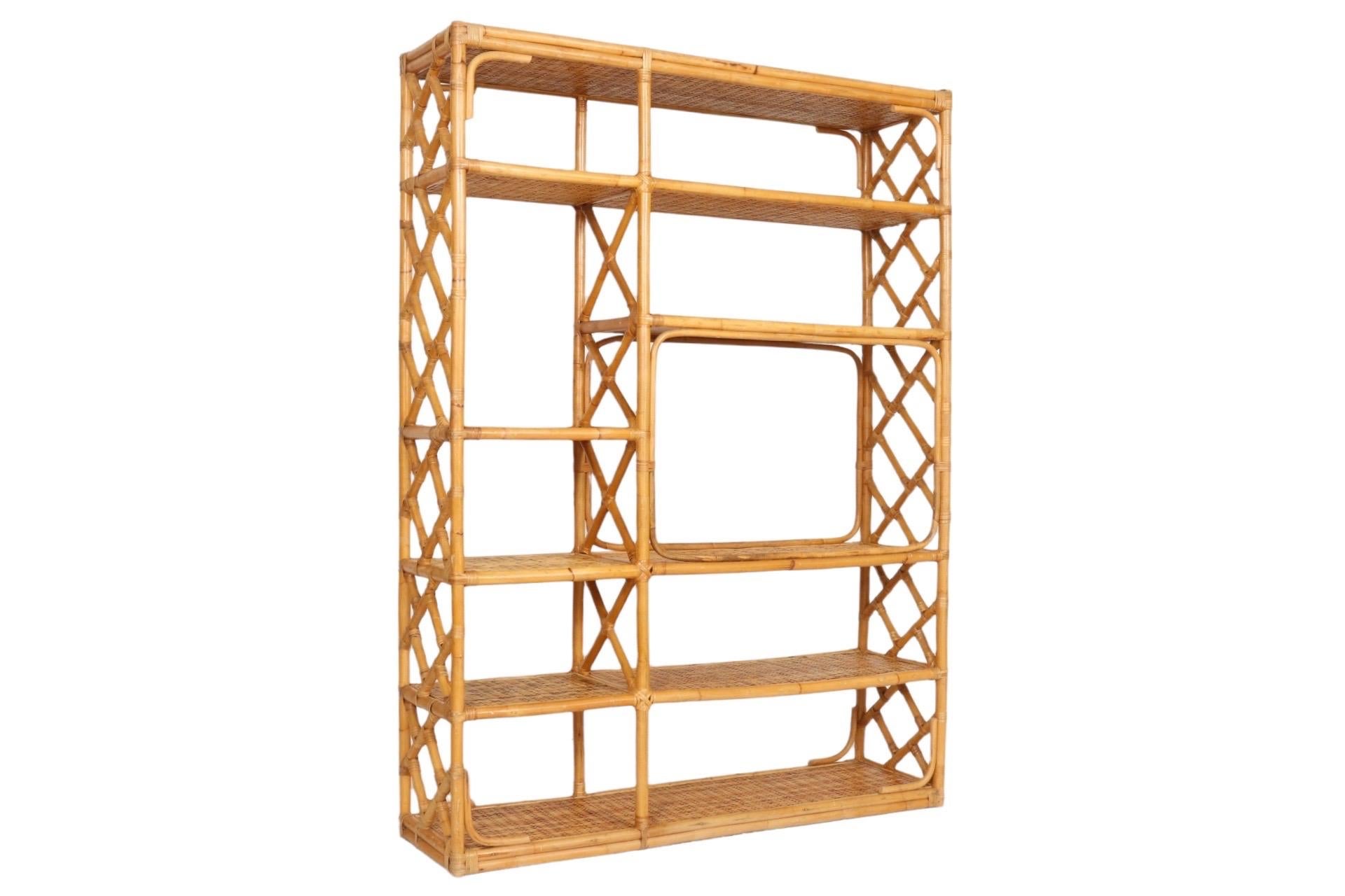 A bamboo and rattan étagère. Thick bamboo pieces form the frame with bentwood bamboo at the corners. Five rattan covered shelves secured with rattan binding are arranged with a large space for a television. The sides are supported with a lattice