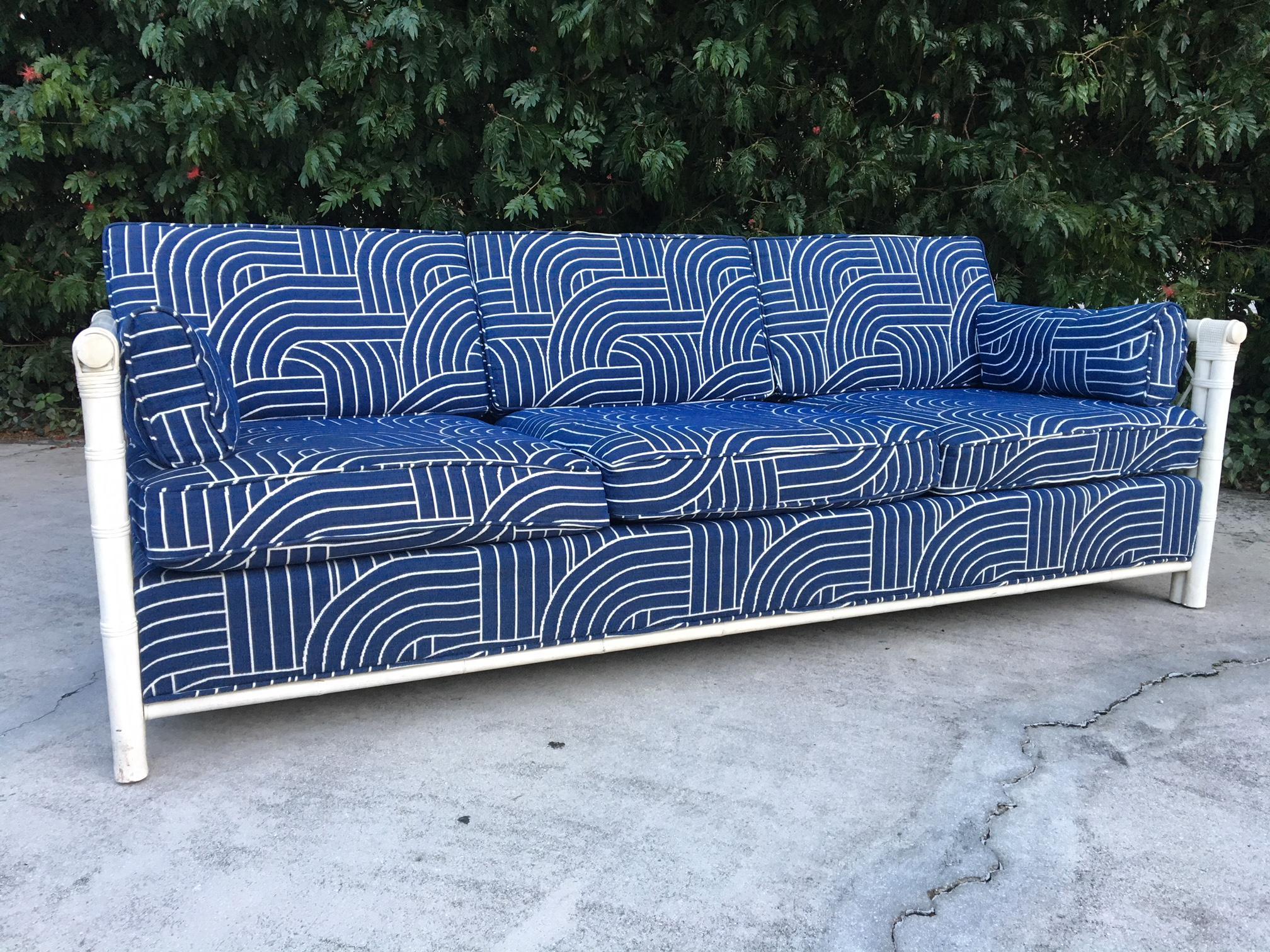 Beautiful rattan sofa features deep blue fabric with a modern print and woven rattan sides. Good vintage condition with no stains or tears to fabric. Minor wear to frame consistent with age.
 