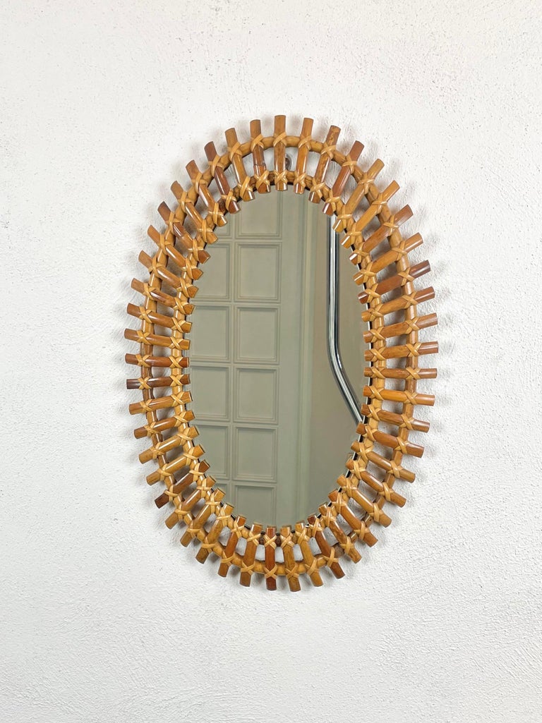 Beautiful oval wall mirror framed by bamboo reeds with contrasting hand-tied caning reed. Made in Italy in the 1960s.