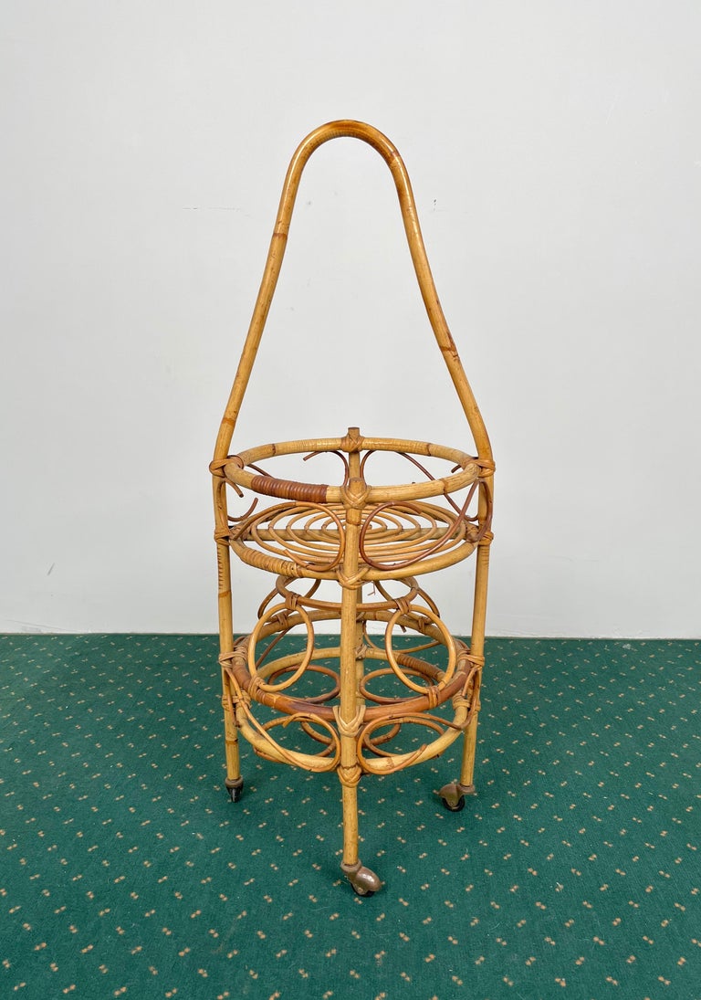 1960s round serving bar cart and bottle holder (up to four bottles) with a long curved handle for lifting in bamboo and rattan made in Italy.