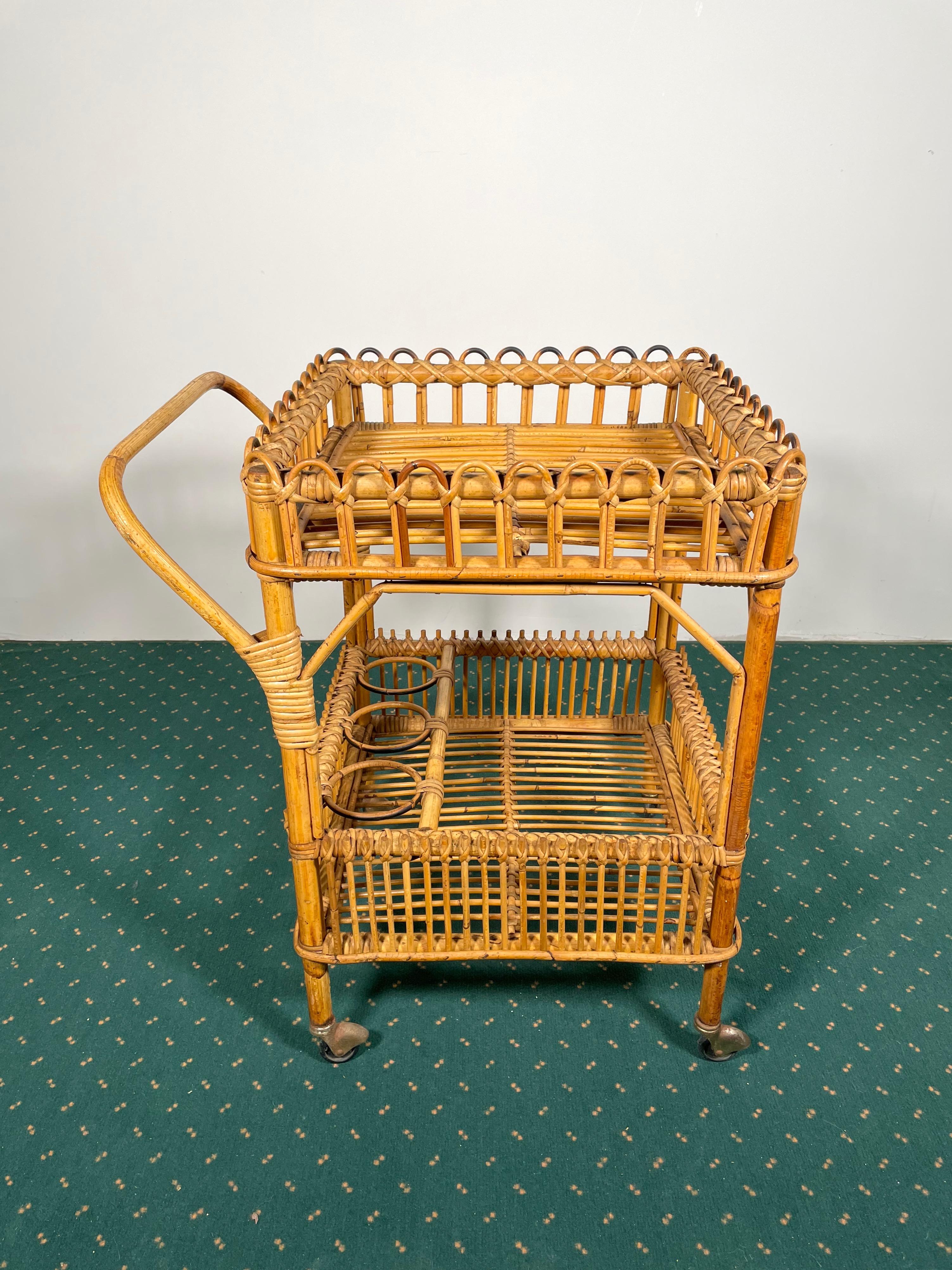 Serving bar cart in bamboo rattan composed of two shelves. The lower one features also three bottle holders. Made in Italy in the 1960s.