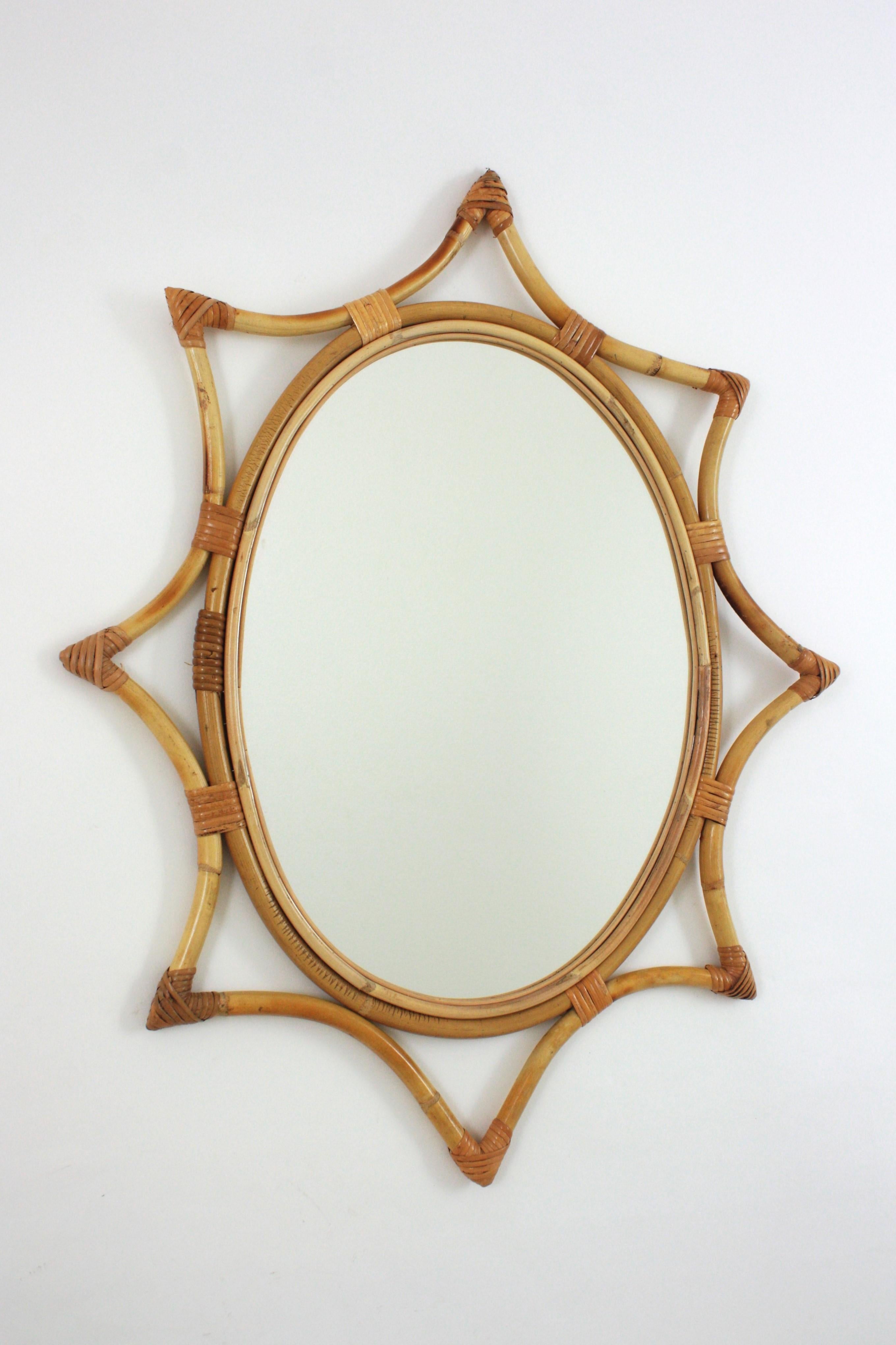 Oval Midcentury bamboo rattan sunburst starburst mirror. Spain, 1960s.
This wall mirror features an oval mirror glass framed by a bamboo star shaped frame with wicker /rattan tied accents.
Beautiful placed alone but also interesting as a part of a