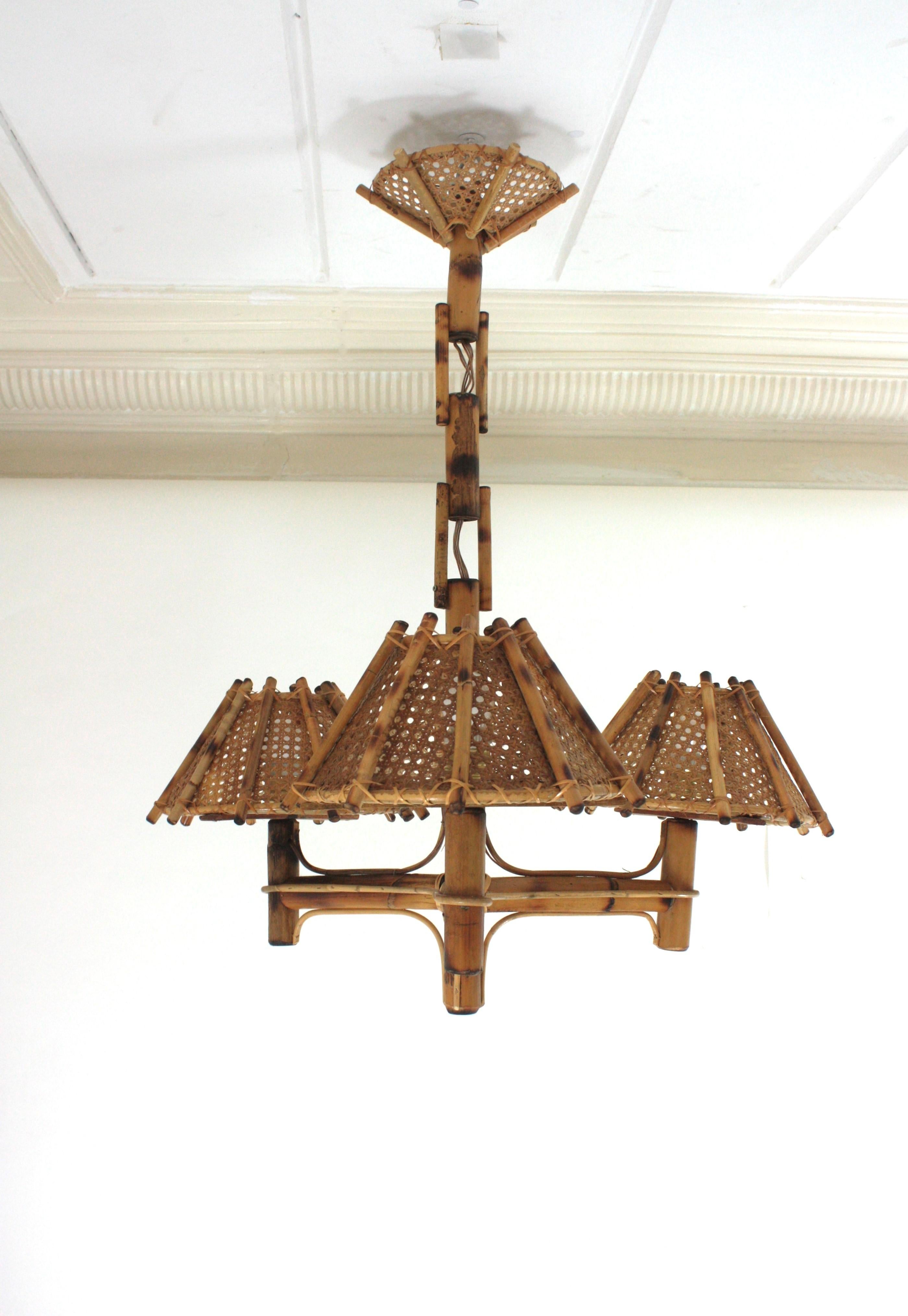 Large Chandelier in Rattan, Italy, 1950s
Mid-Century Modern bamboo chandelier with Rattan or Wicker Weave Lampshades.
This eye-catching chandelier features a bamboo structure with three arms holding woven wicker wire conical lampshades. A bamboo