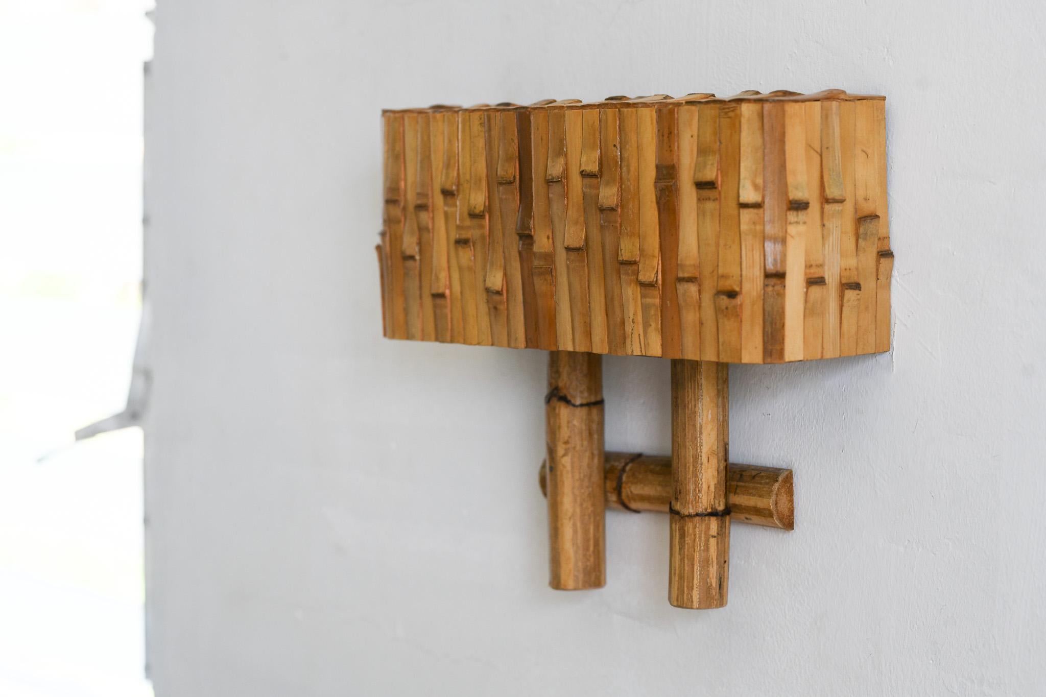 Cette lampe murale en bambou et rotin allie le style moderne du milieu du siècle à une belle texture organique. Fabriqué à la main avec précision, il apportera une touche d'élégance à n'importe quelle pièce. Les éléments naturels du bambou et du