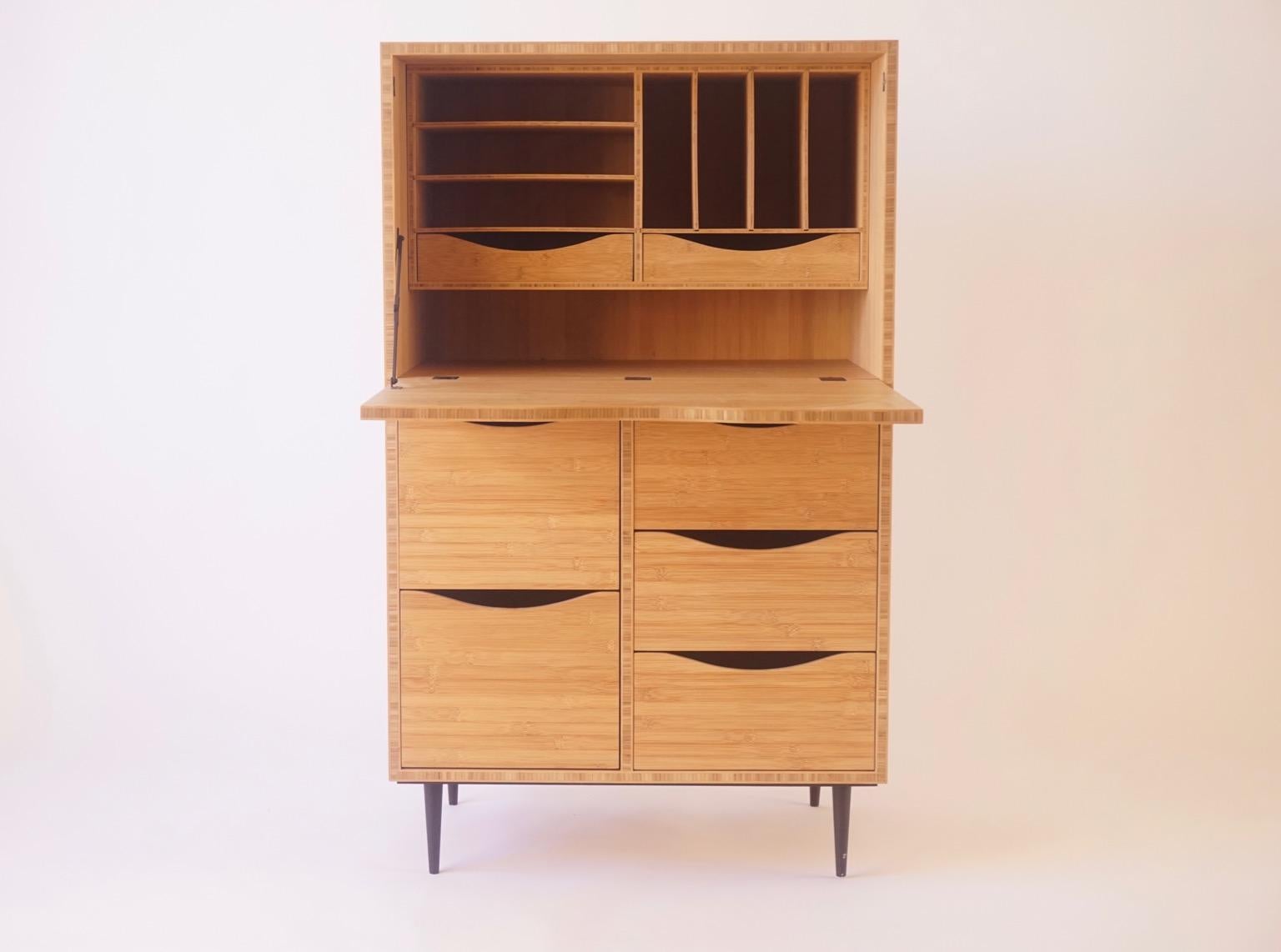 The bamboo secretary is a contemporary take on a traditional cabinet used for letter writing. The beautiful bronze hinges are contrasted with a modern bamboo laminate product for the case, with turned metal legs. All the drawers run on bamboo slats