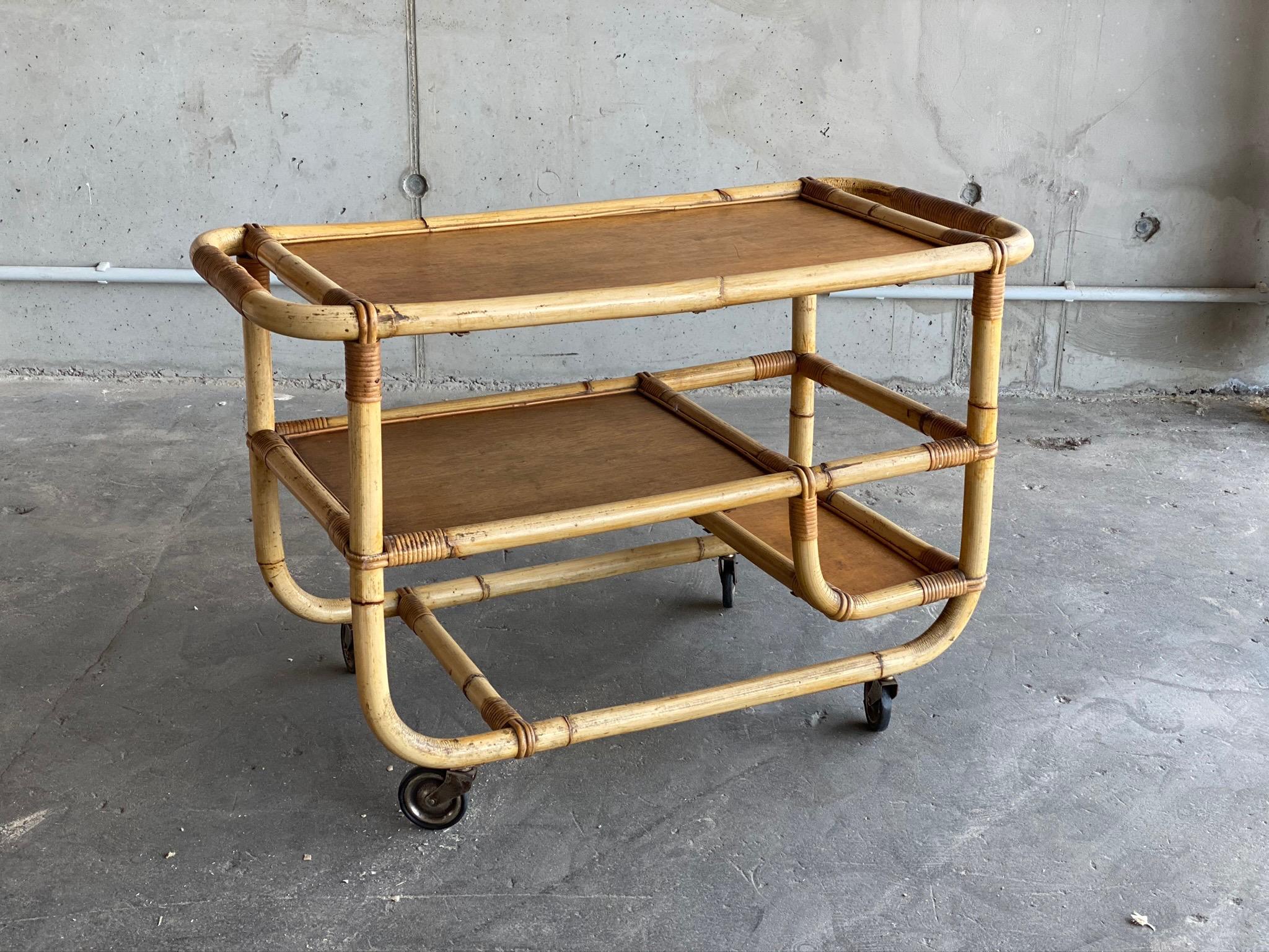 A charming serving trolley from the 1940s. The trolley comes on wheels and is made of bamboo and rattan. Its geometric, linear design is reminiscent of Art Deco furniture design from the 1920s, while the choice of materials is typical of the 1950s.