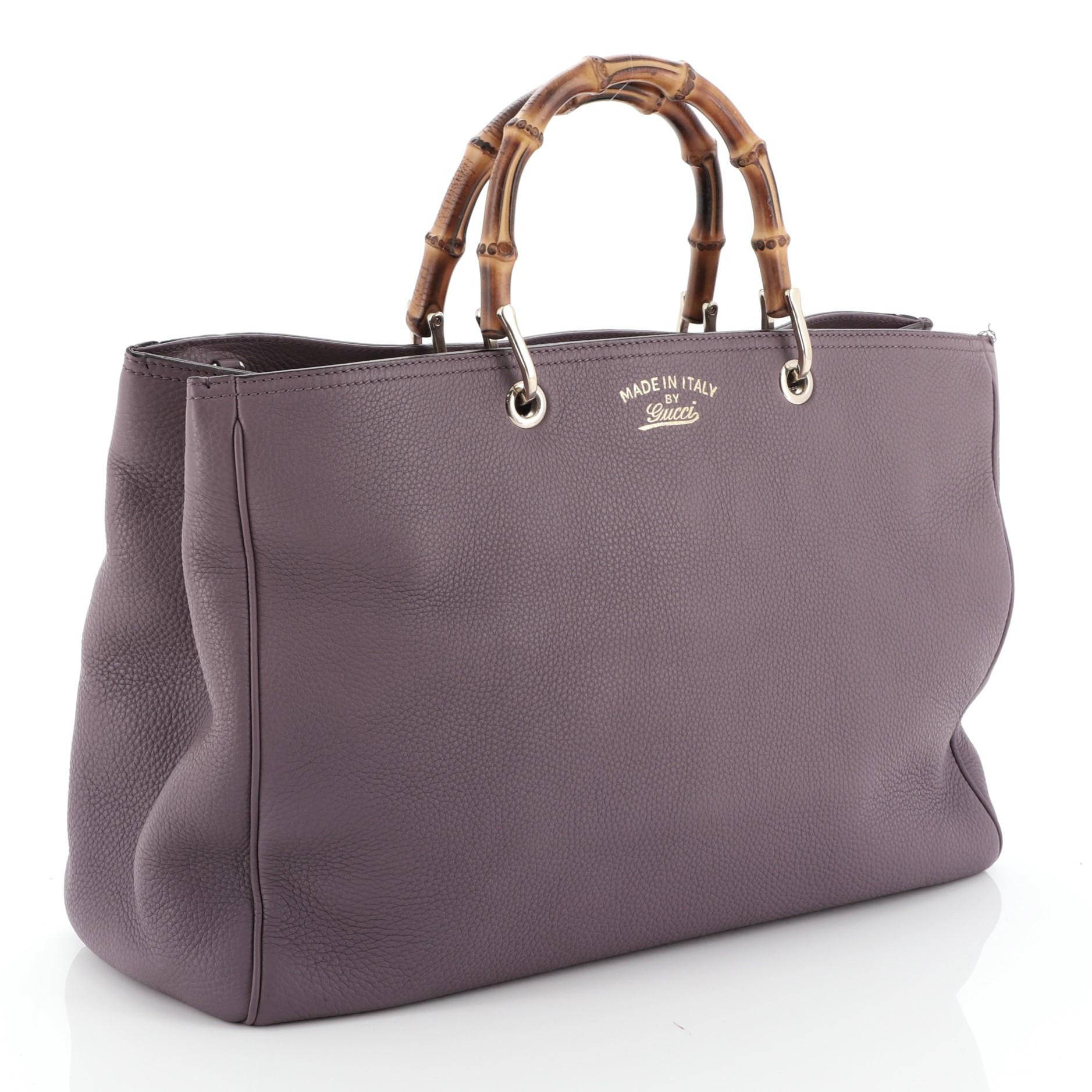 This Gucci Bamboo Shopper Tote Leather Large, crafted from purple leather, features bamboo top handles, stamped logo at the front and gold-tone hardware. Its hidden magnetic snap closure opens to a neutral fabric interior with middle zip compartment