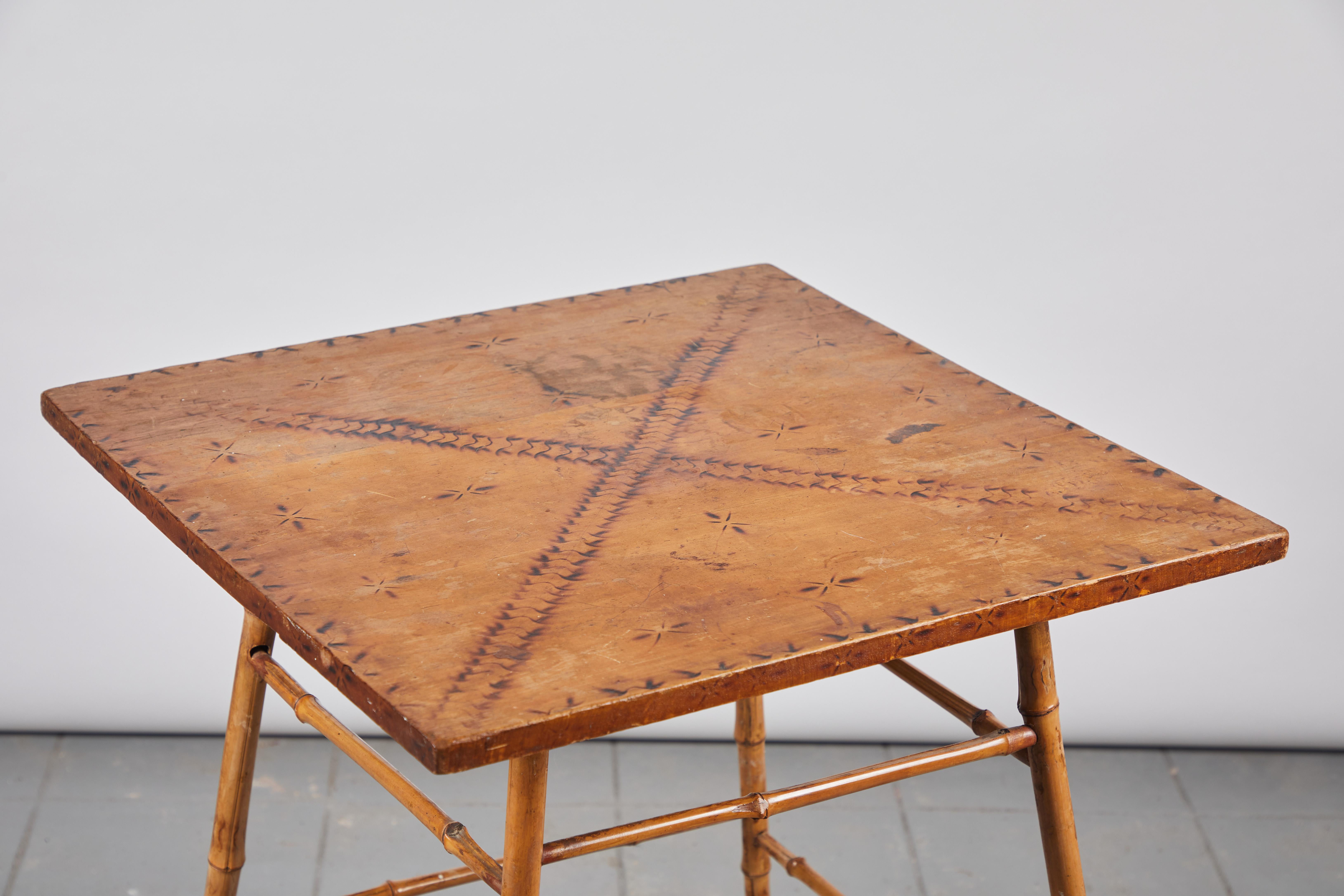 Bamboo side table with wooden top with darkened stenciled details.