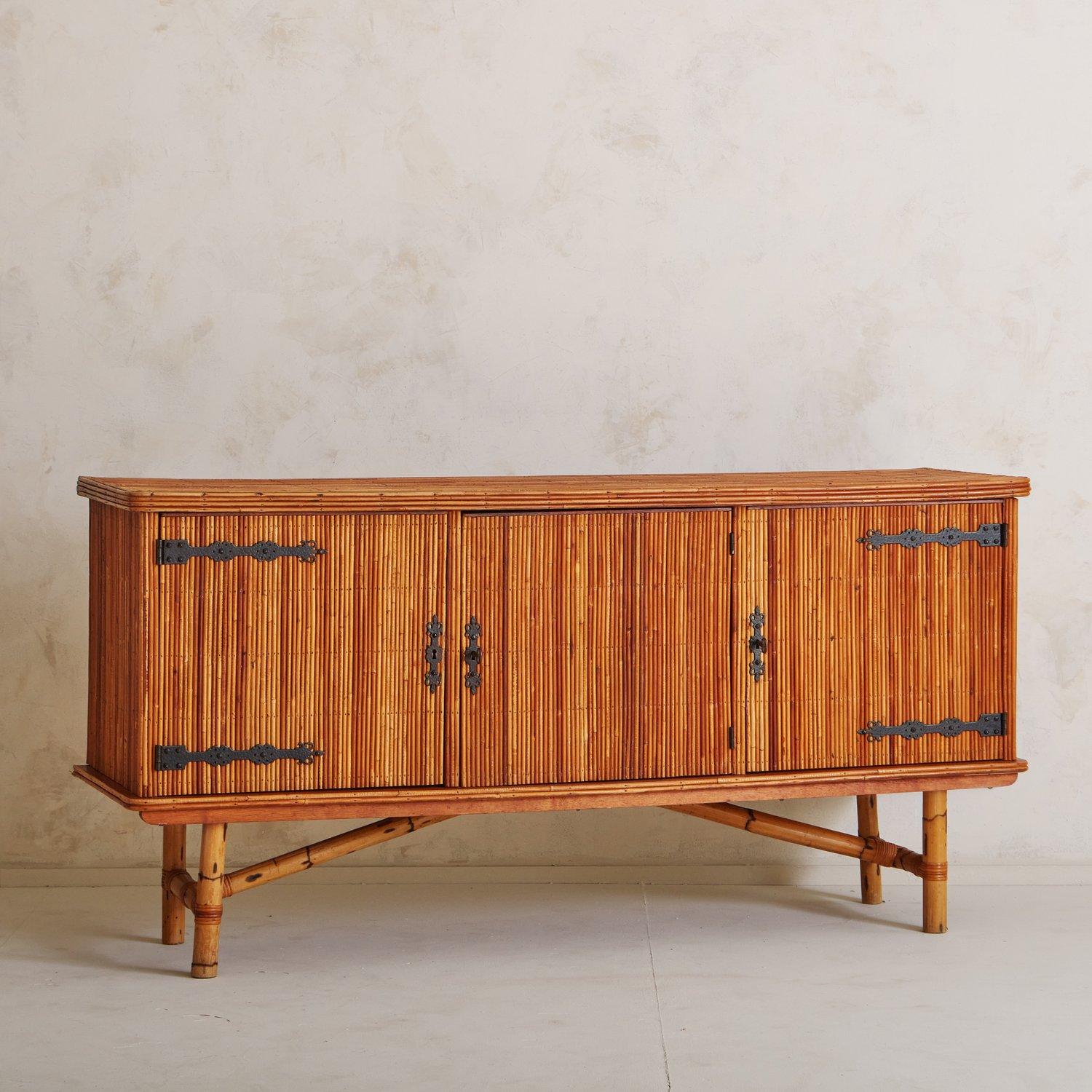 A 1950s French bamboo sideboard attributed to Audoux & Minet. This piece features hand-forged iron hardware and beautiful natural color variations in the bamboo. It has three cabinet doors which open to reveal a black painted interior with one