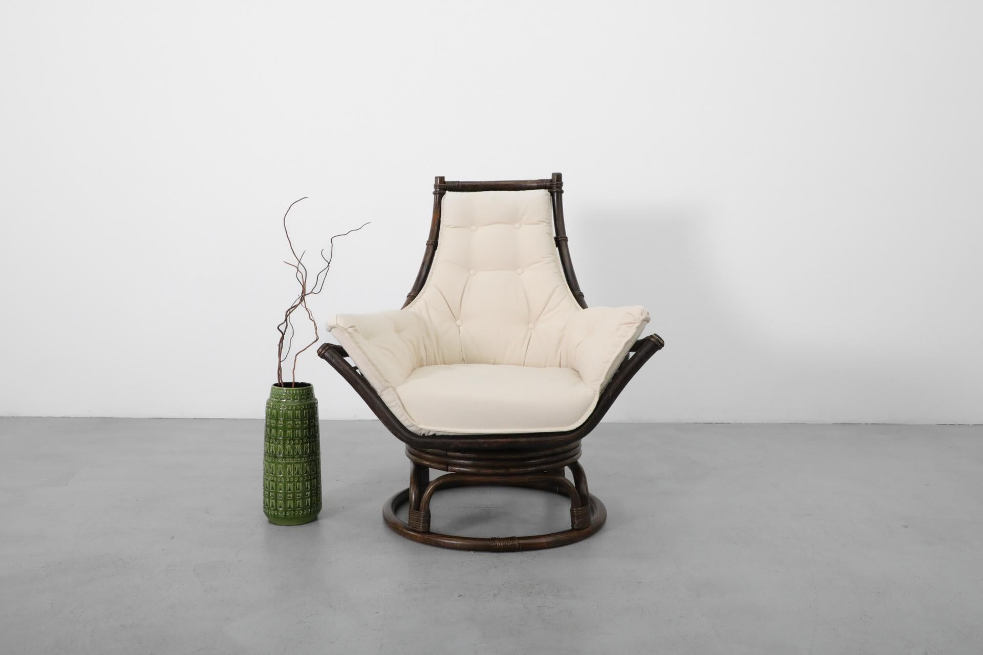 Chaise de salon pivotante en bambou foncé avec coussin en toile naturelle nouvellement rembourré. Cadre légèrement remis à neuf avec quelques traces d'usure, y compris des rayures, correspondant à l'âge et à l'utilisation.