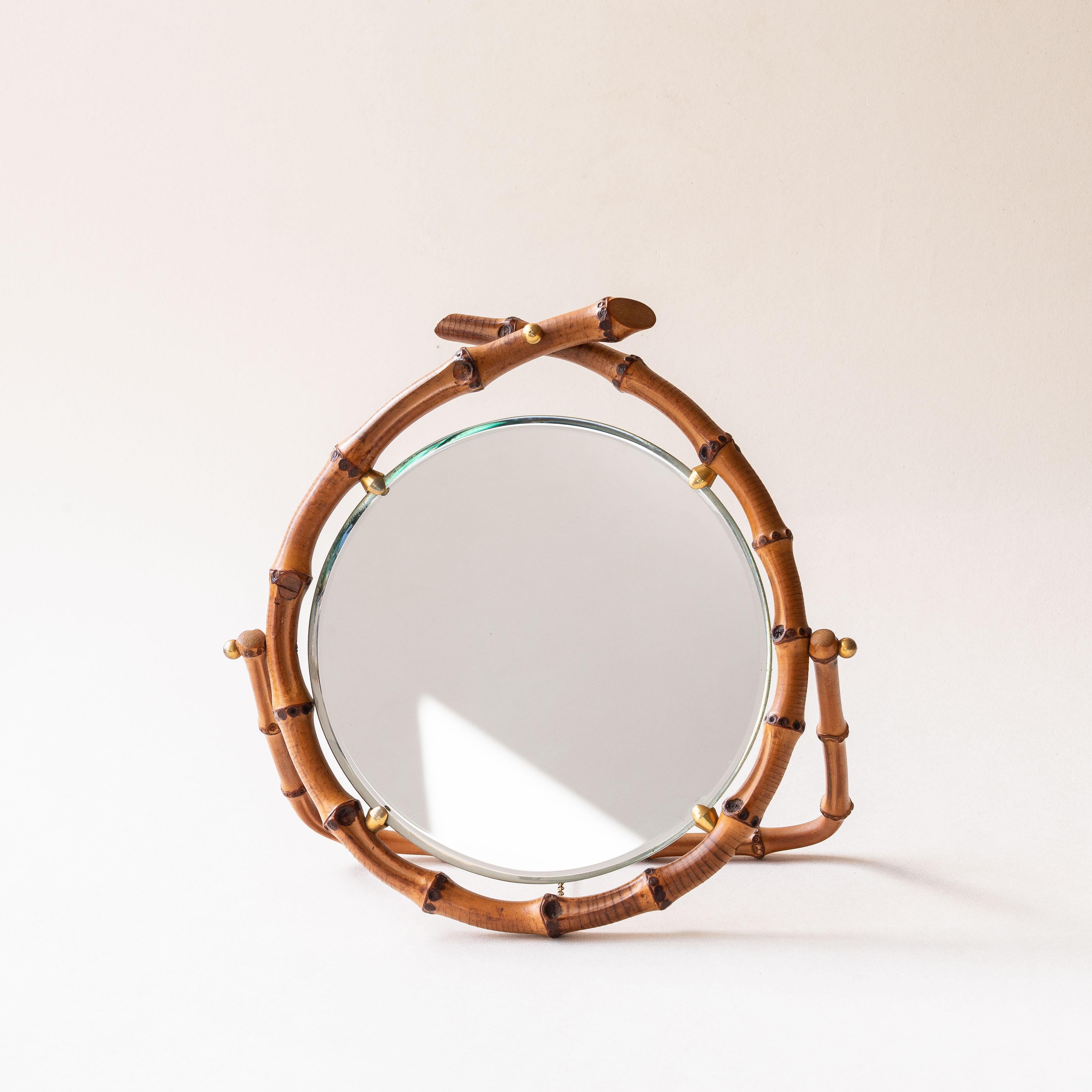 Bamboo Table Mirror, Revolving Vanity Mirror, France 1960s

Rare and chic 1960s table mirror, crafted from natural bamboo and brass details.

The mirror sits on a delicately designed stand, completed with a brass chain for added stability. 

Perfect