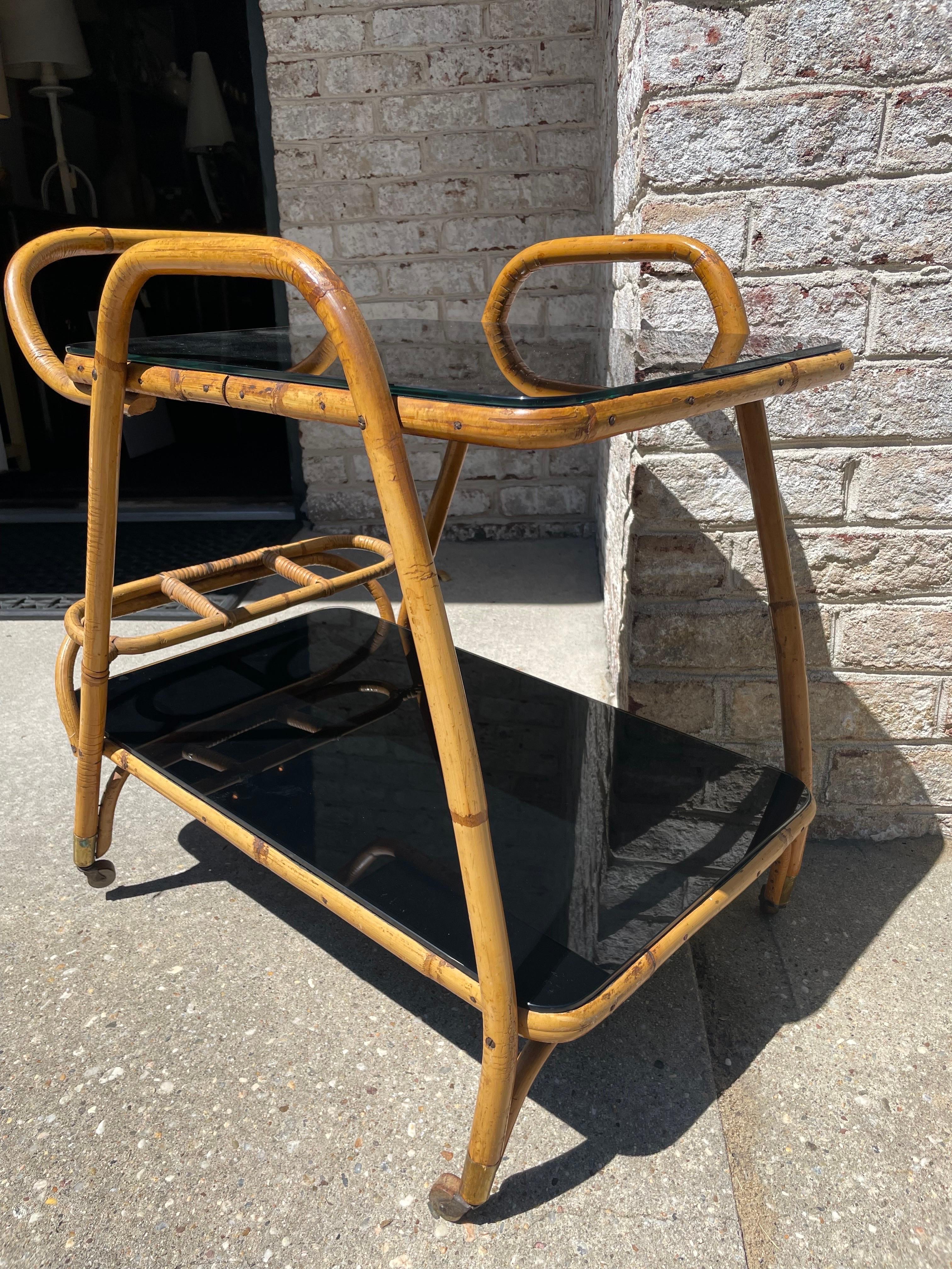 A fantastic bent bamboo trolley cart with bottle holder dividers. This piece has its original blue laminate design and black glass tops which were added later to really elevate the beauty of this Italian mid-century design. Glass can be removed