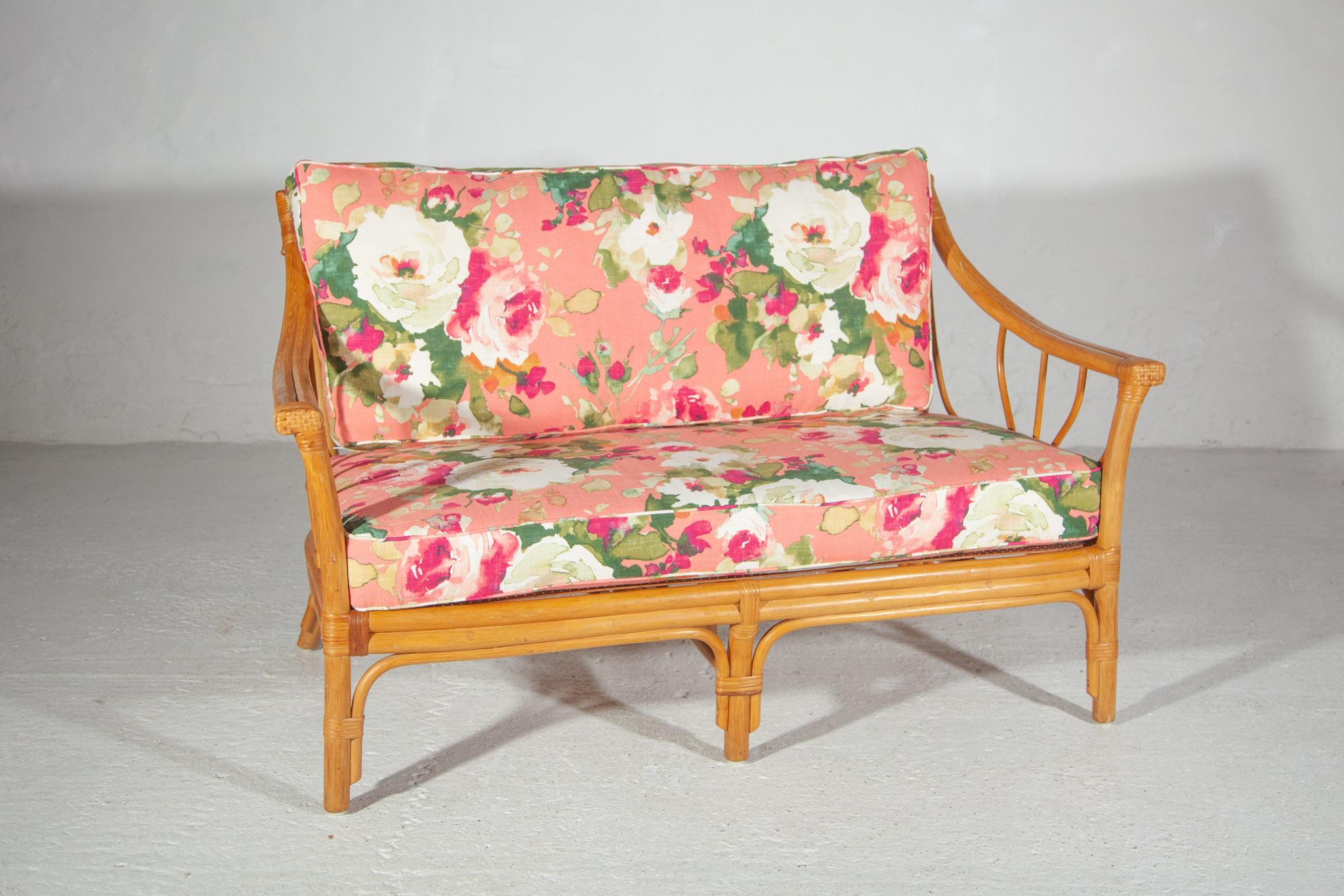 Very stylish quality vintage bamboo sofa, two-seater. The two-seater has renewed upholstered cushions in a soft color floral outdoor fabric. 
Includes two matching lounge chairs see our other upload. The set can be used well on your patio or in