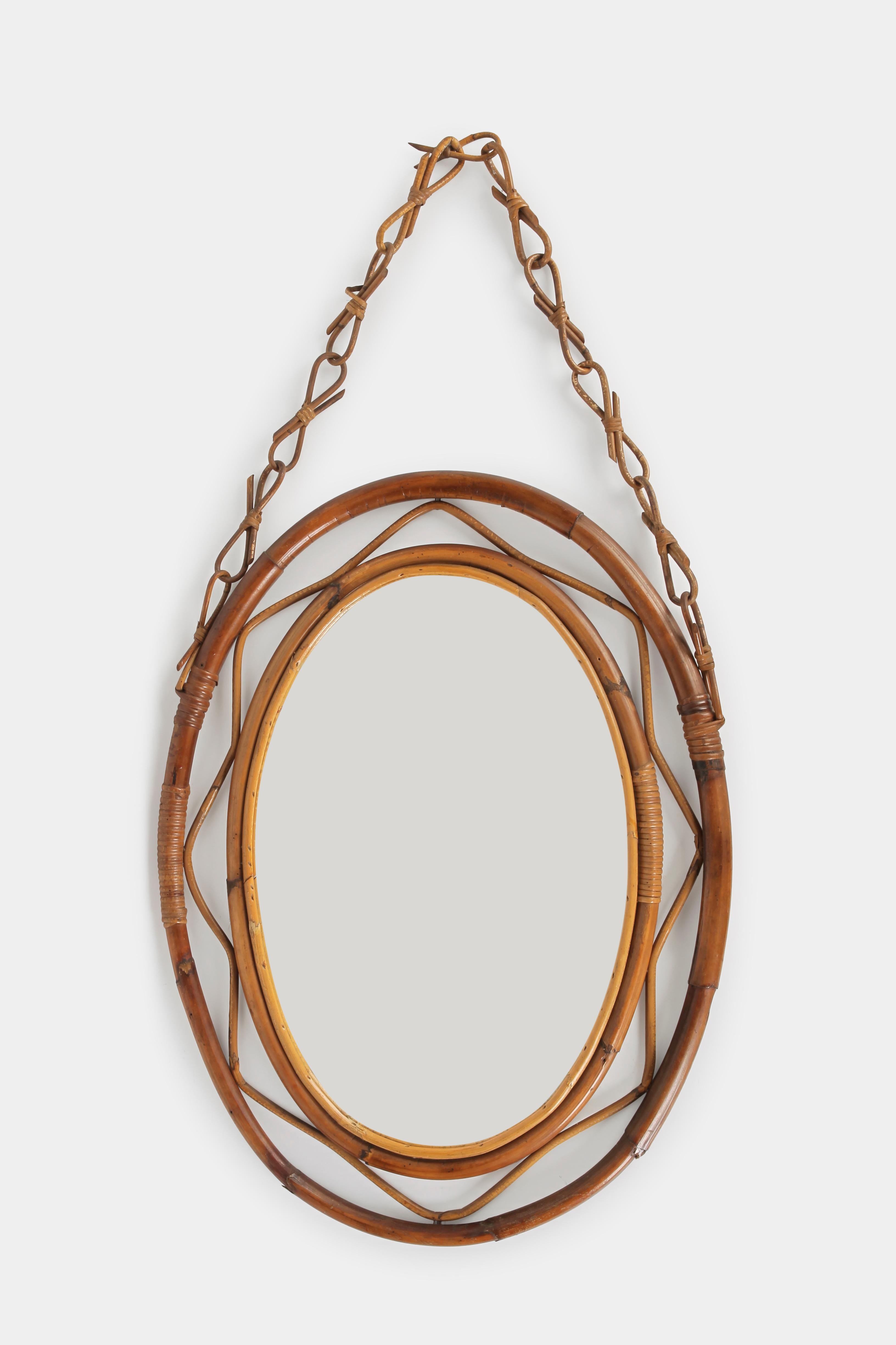 Gorgeous oval bamboo cane mirror from the 1960s with a bamboo chain for hanging. Made by the company Bonacina in Italy. In very good condition. A great piece for any room.