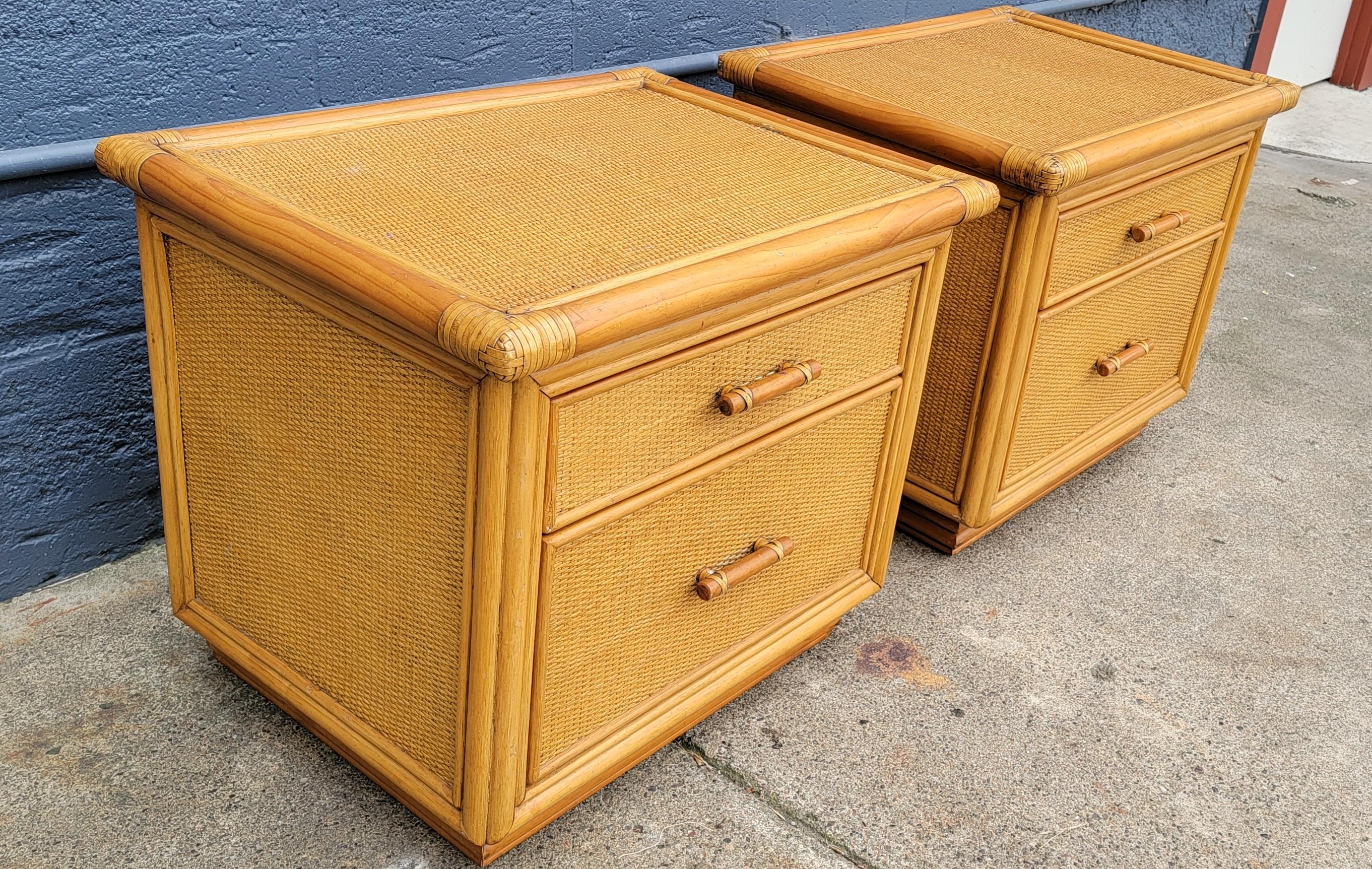 A pair of bamboo and wicker / rattan organic modern end tables or nightstands. Circa. 1970's. Each cabinet has 2 drawers with steel glides that function effortlessly. Very good original vintage condition with light wear / patina from use and history.
