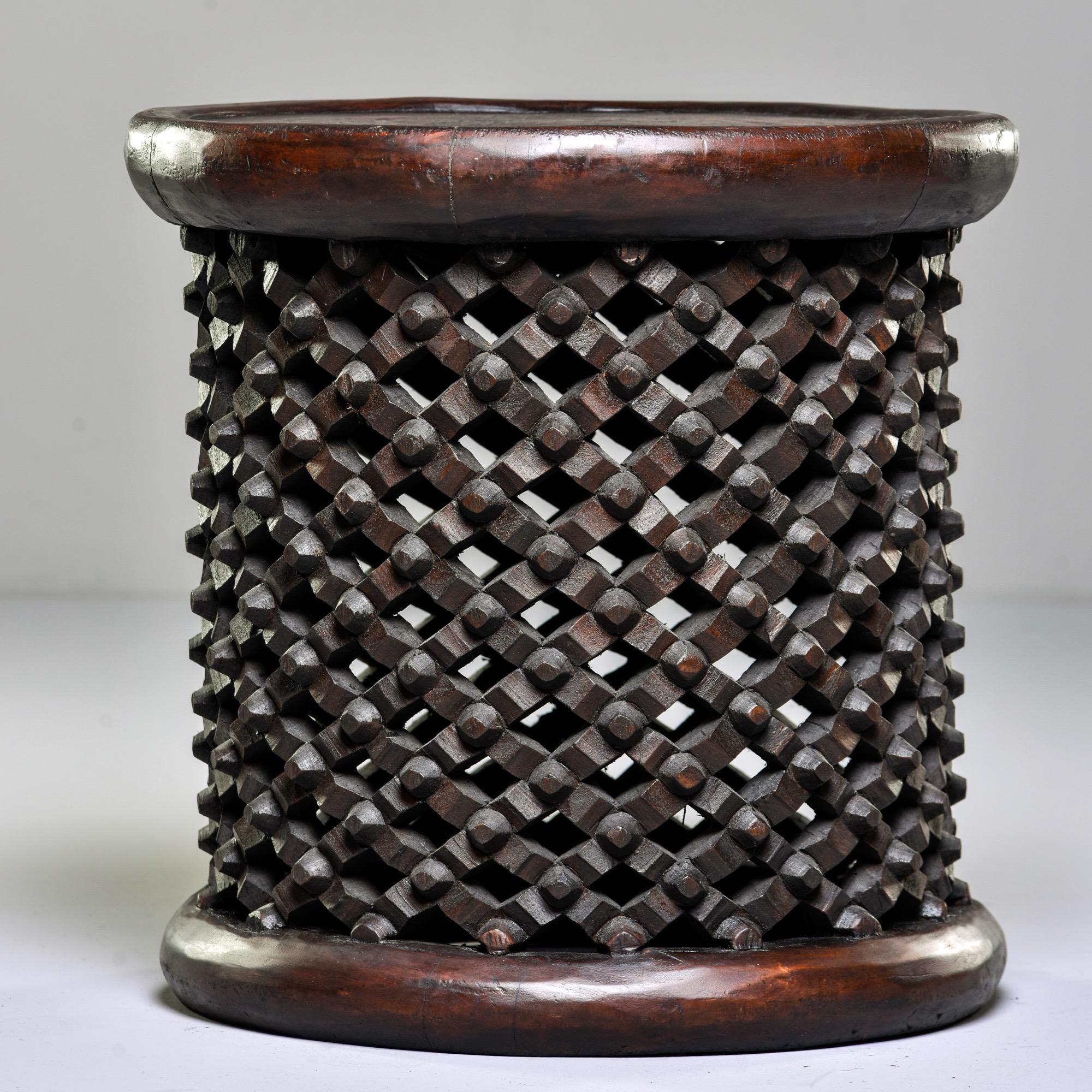 Round dark wood stool or side table, circa 1980s. Hand-carved by a tribal artist in Cameroon, this style is known as a spider stool because of its knobby web-like base. The Bamileke people see spiders as a link between the living and the dead and