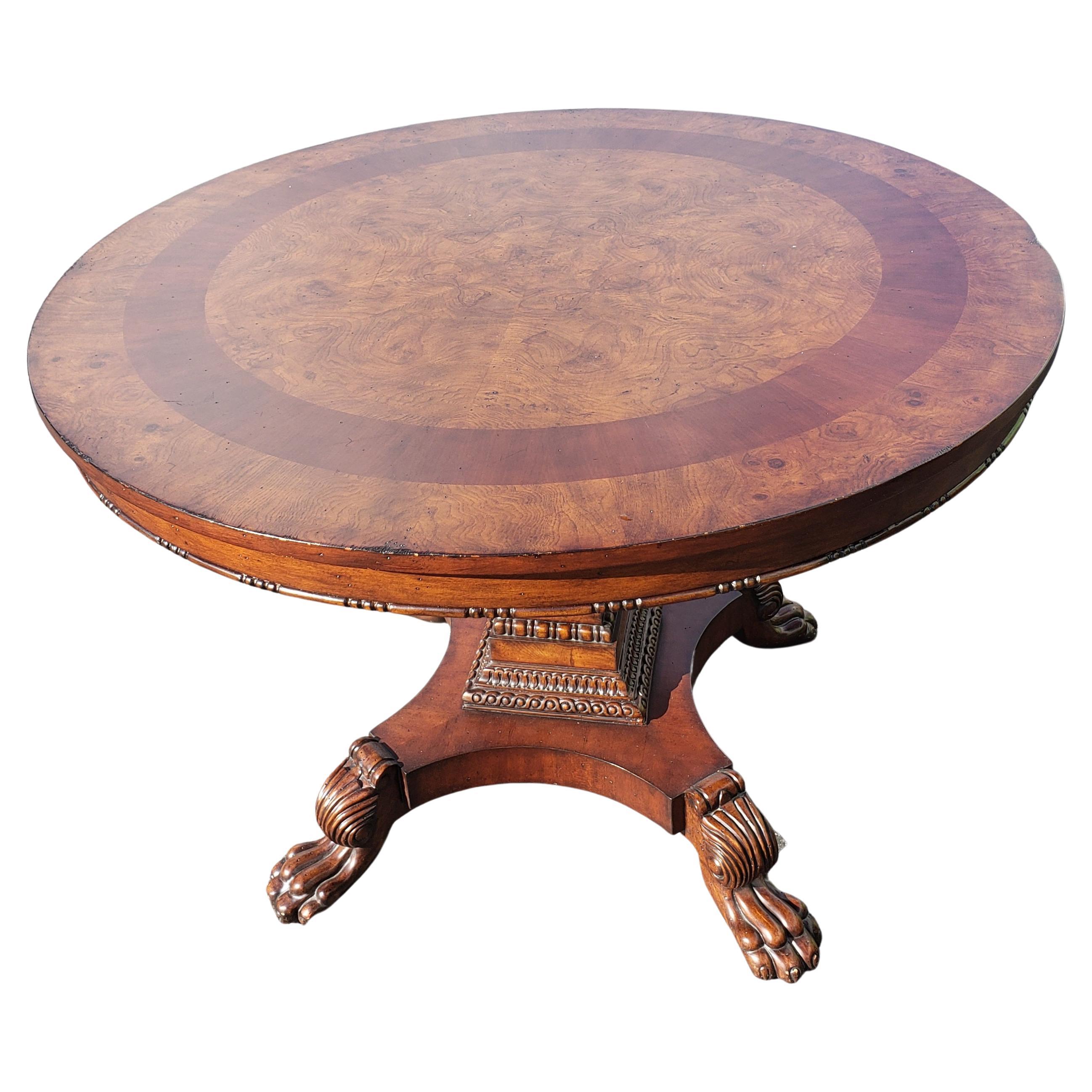 Exquisite book matched burl walnut veneered top with Mahogany banded inlay over a similarly veneered quad part pedestal and stepped base. Pedestal with fine carving details ending with large lion paw feet. Manufacturer's distressed top and pedestal.