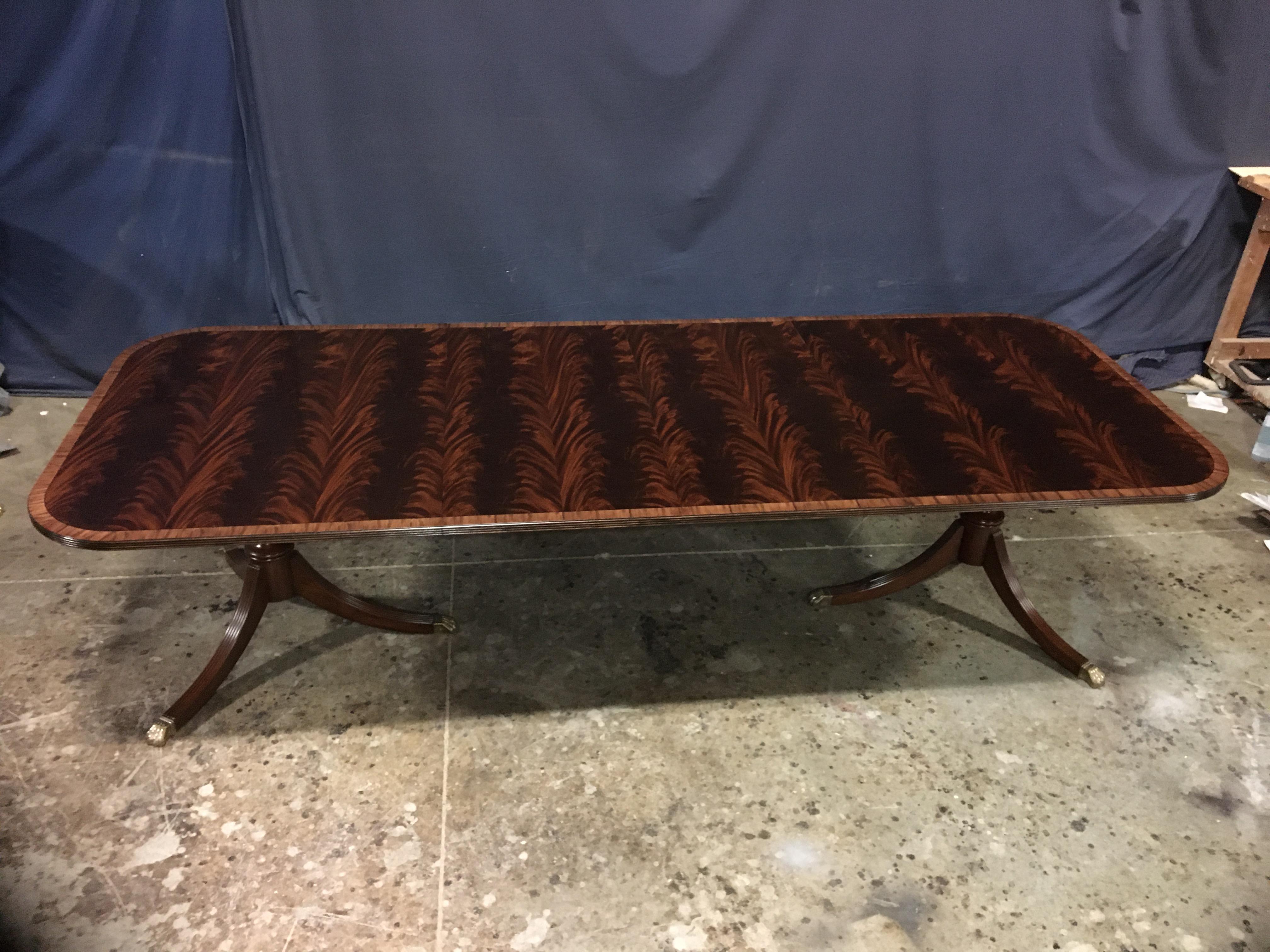 This is a made to order traditional mahogany dining table made in the Leighton Hall shop. It features a field of slip-matched swirly crotch mahogany from West Africa. It has a satinwood border and a three beaded edge. It has a hand rubbed and
